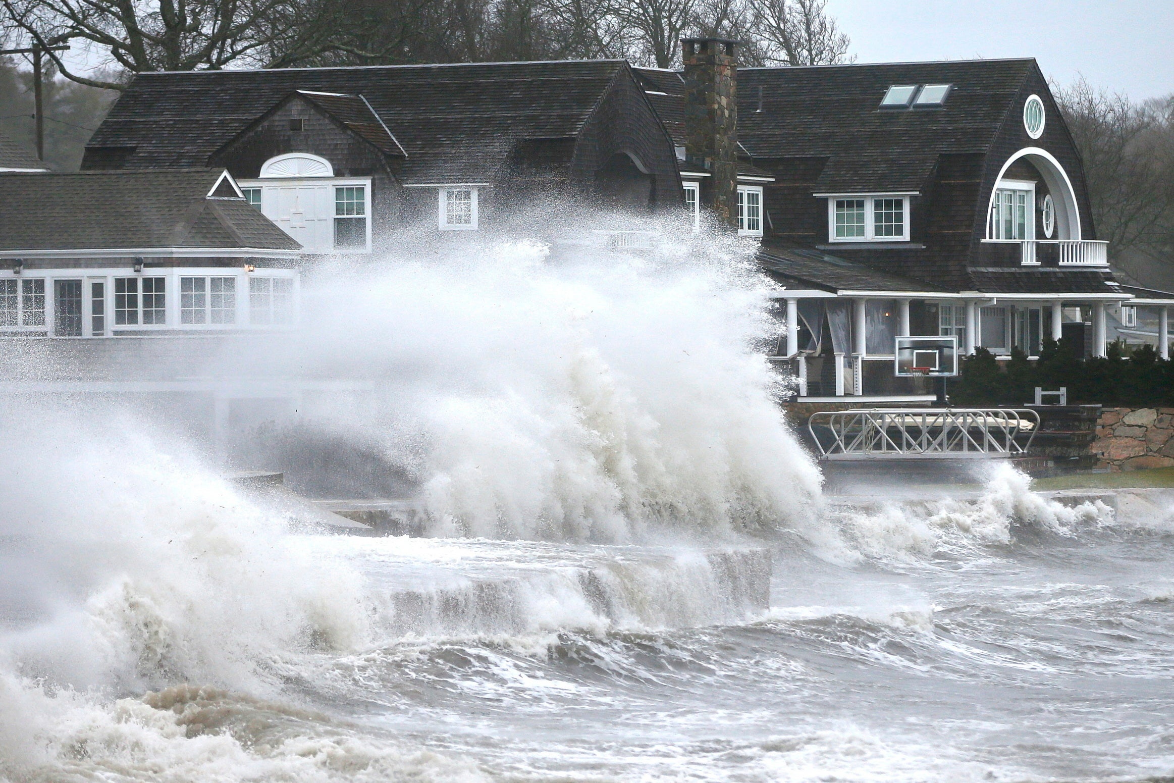 High winds drive surf into a retaining wall in front of a residence in Mattapoisett, Mass