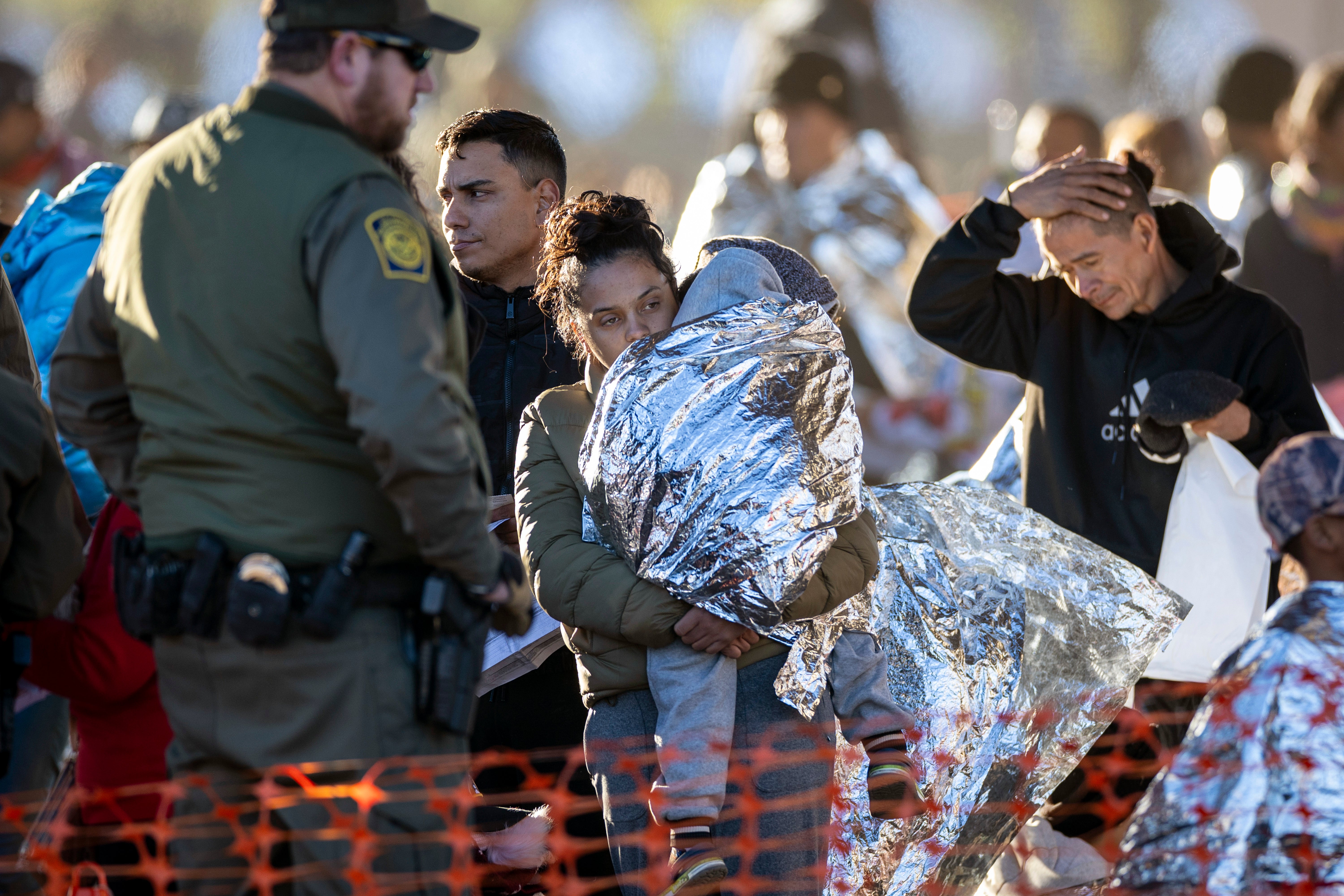 A US Border Patrol agent watches as migrants arrive at a transit centre near the US-Mexico border in Texas on 19 December.