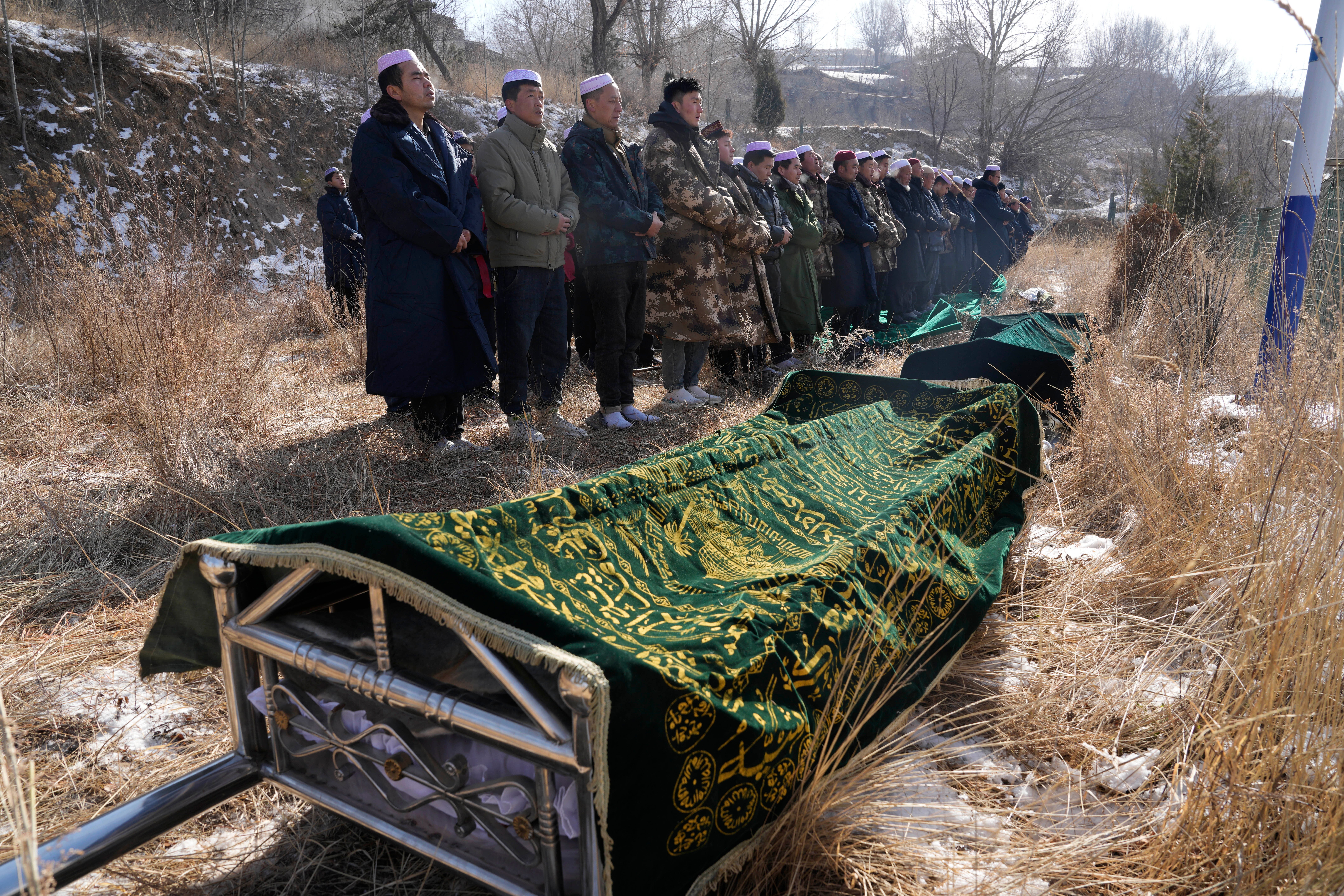 Ma Lianqiang, left, stands near the body of his wife Han Suofeiya, who was killed in the village of Yangwa