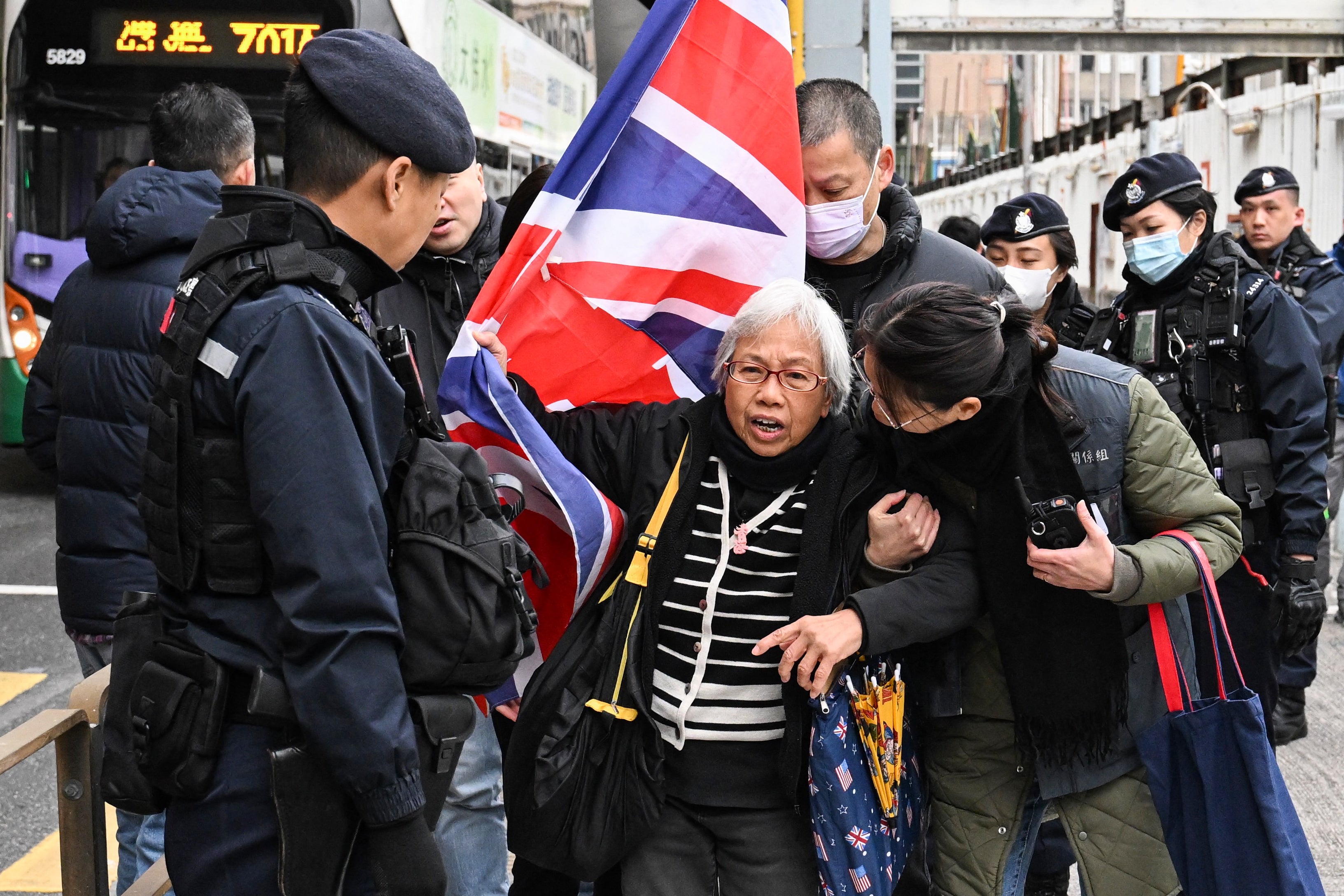 Policemen stop activist Alexandra Wong, also known as Grandma Wong, as she carries a union flag outside the West Kowloon court ahead of the trial of pro-democracy media tycoon Jimmy Lai on Friday