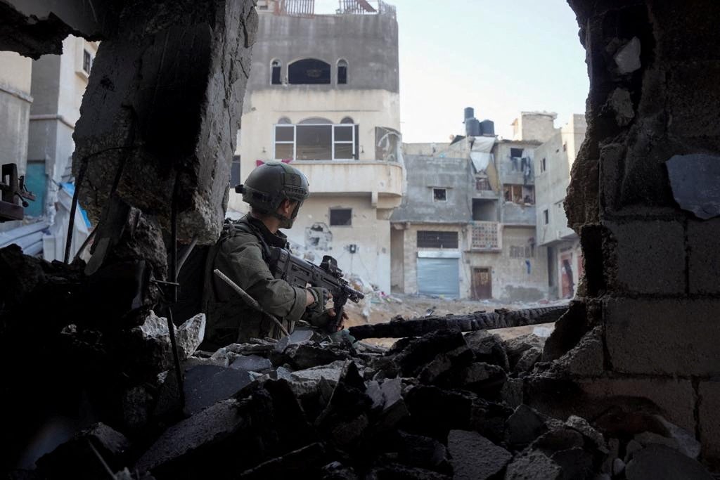 An Israeli solider stands next to a destroyed building in Khan Younis, southern Gaza