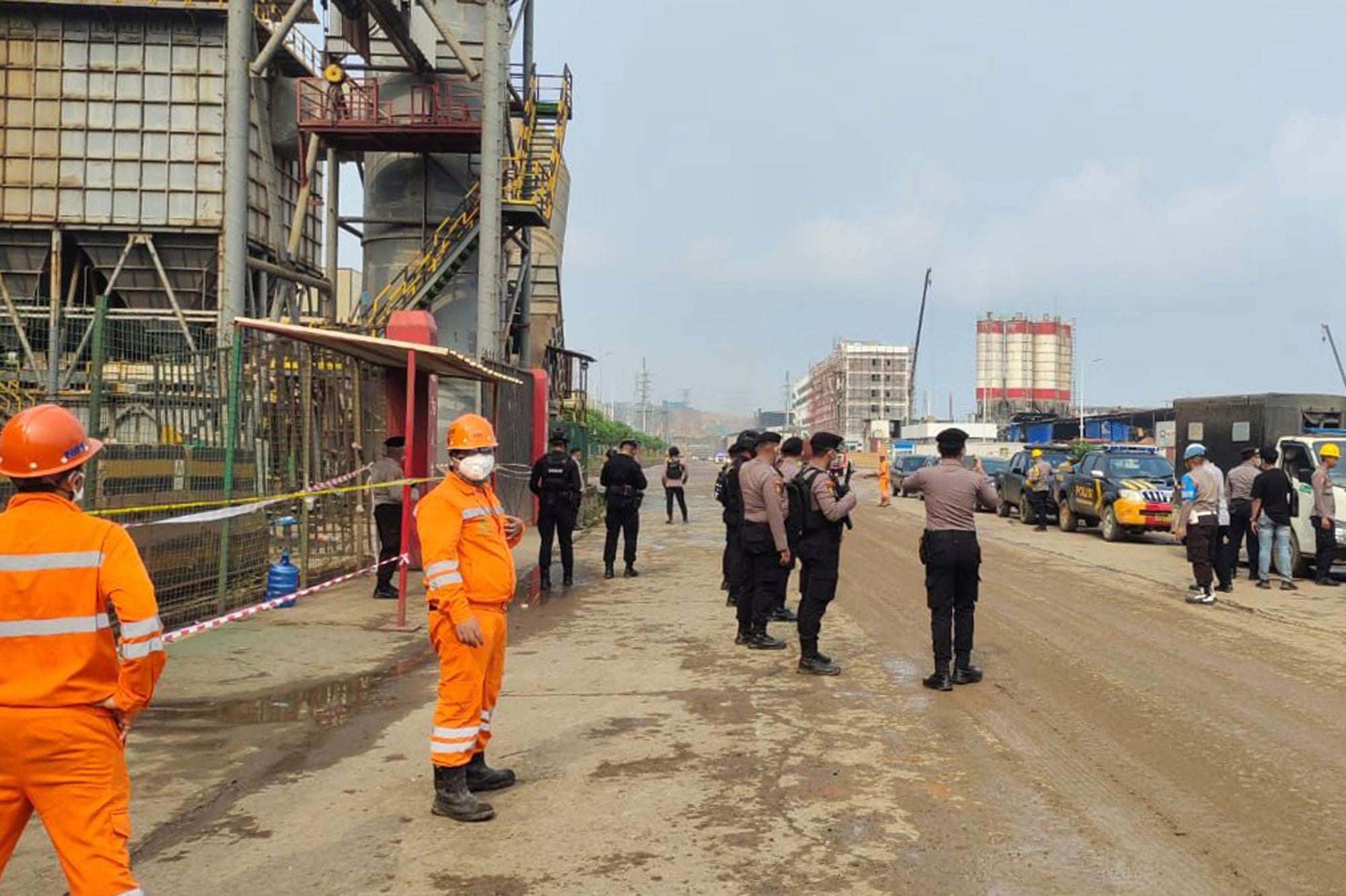 Police officers and workers stand near the site where a furnace explosion occurred at PT Indonesia Tsingshan Stainless Steel smelting plant in Morowali