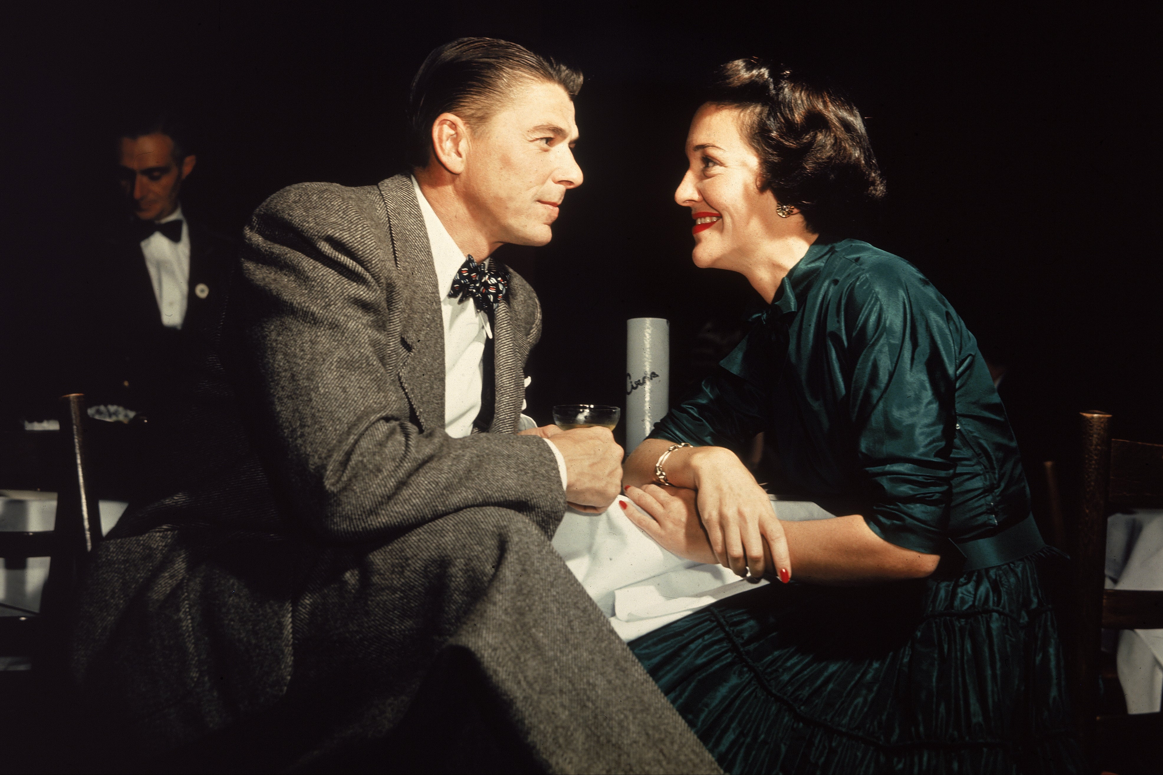 Ronald Reagan and his wife Nancy Reagan gaze at one another across a table, circa 1952