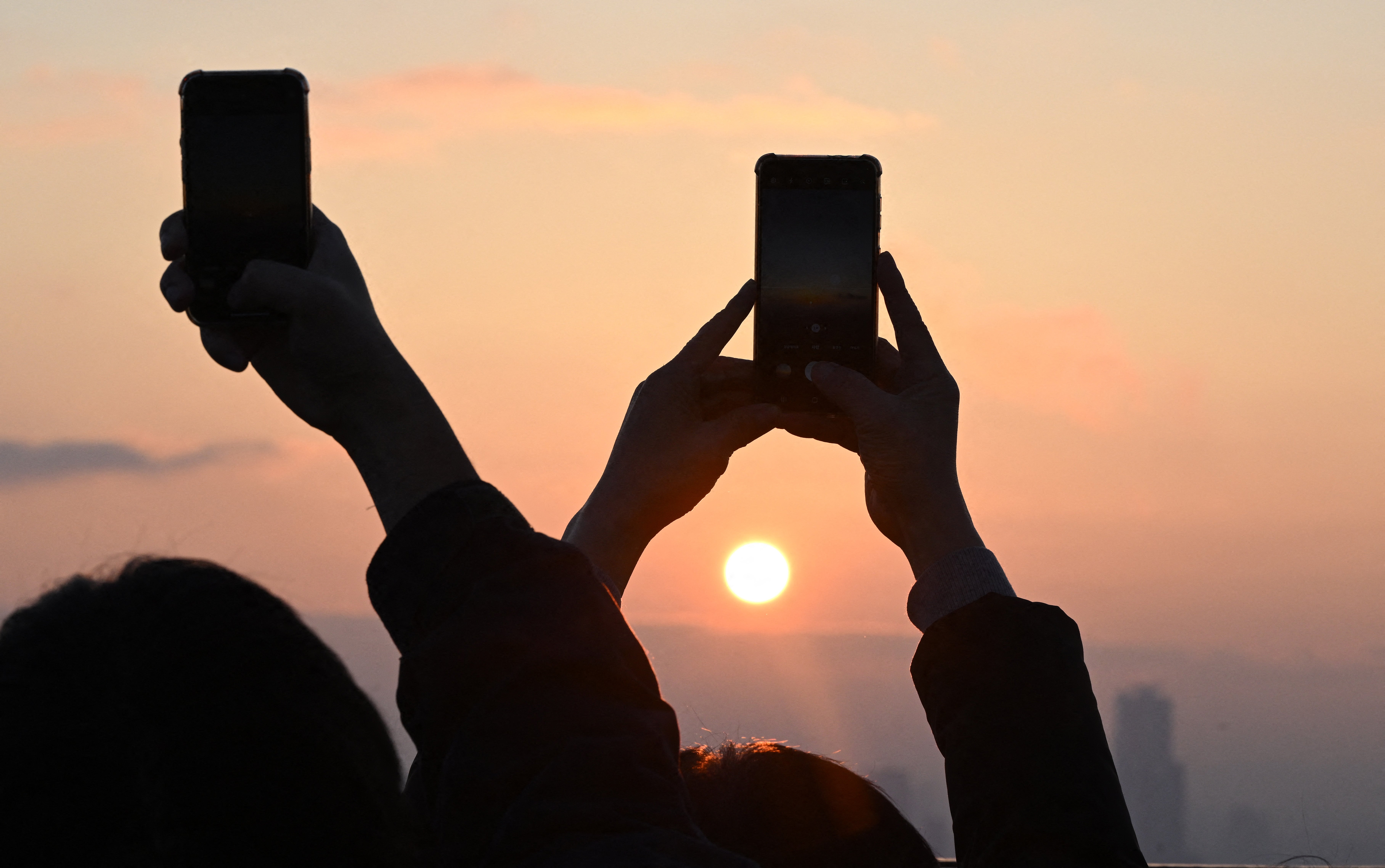 People take pictures as they observe the last sunset of the year on a viewing deck at Namsan tower in Seoul