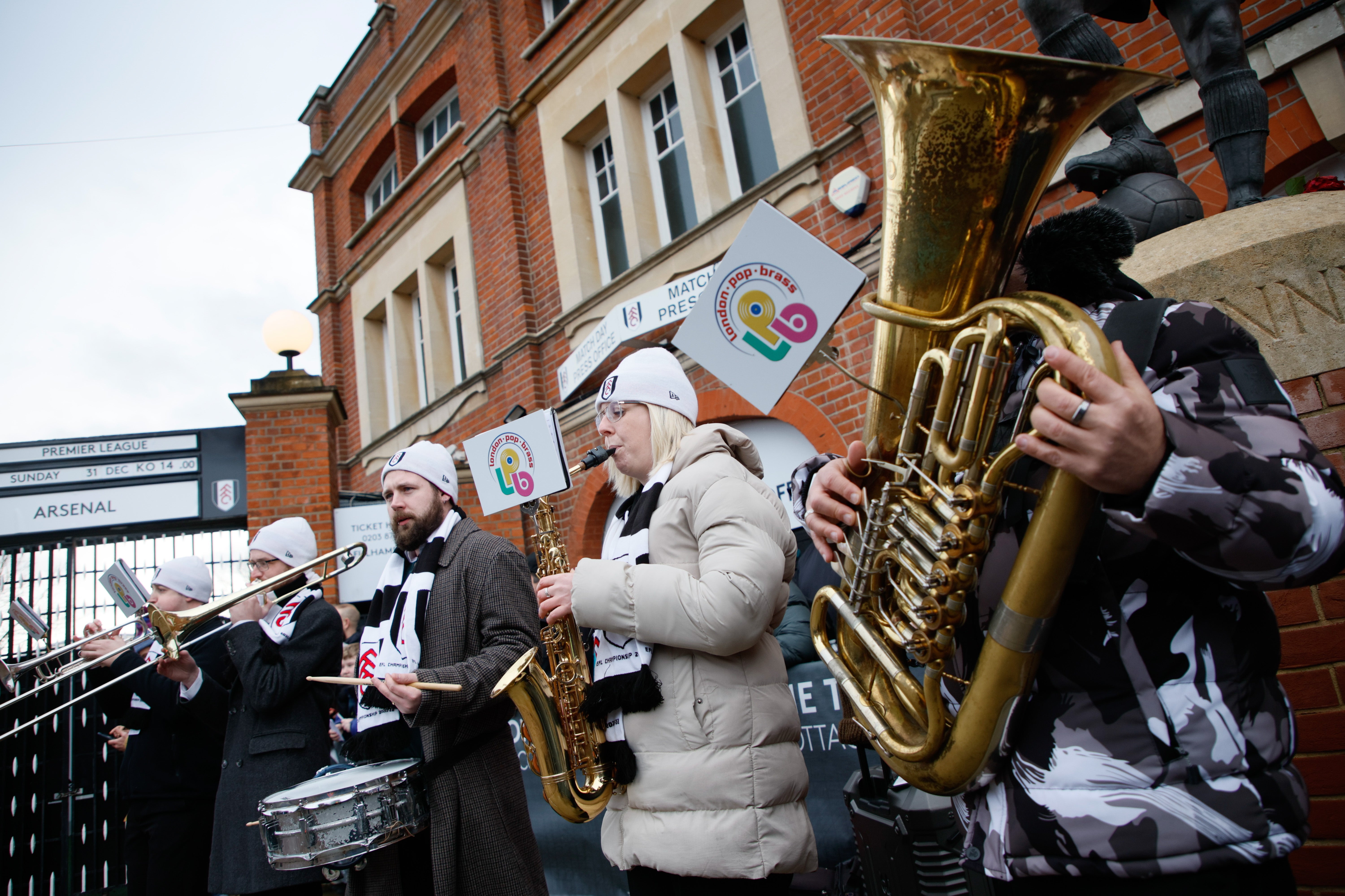 A brass band plays outside Craven Cottage stadium ahead of the English Premier League match between Fulham FC and Arsenal FC