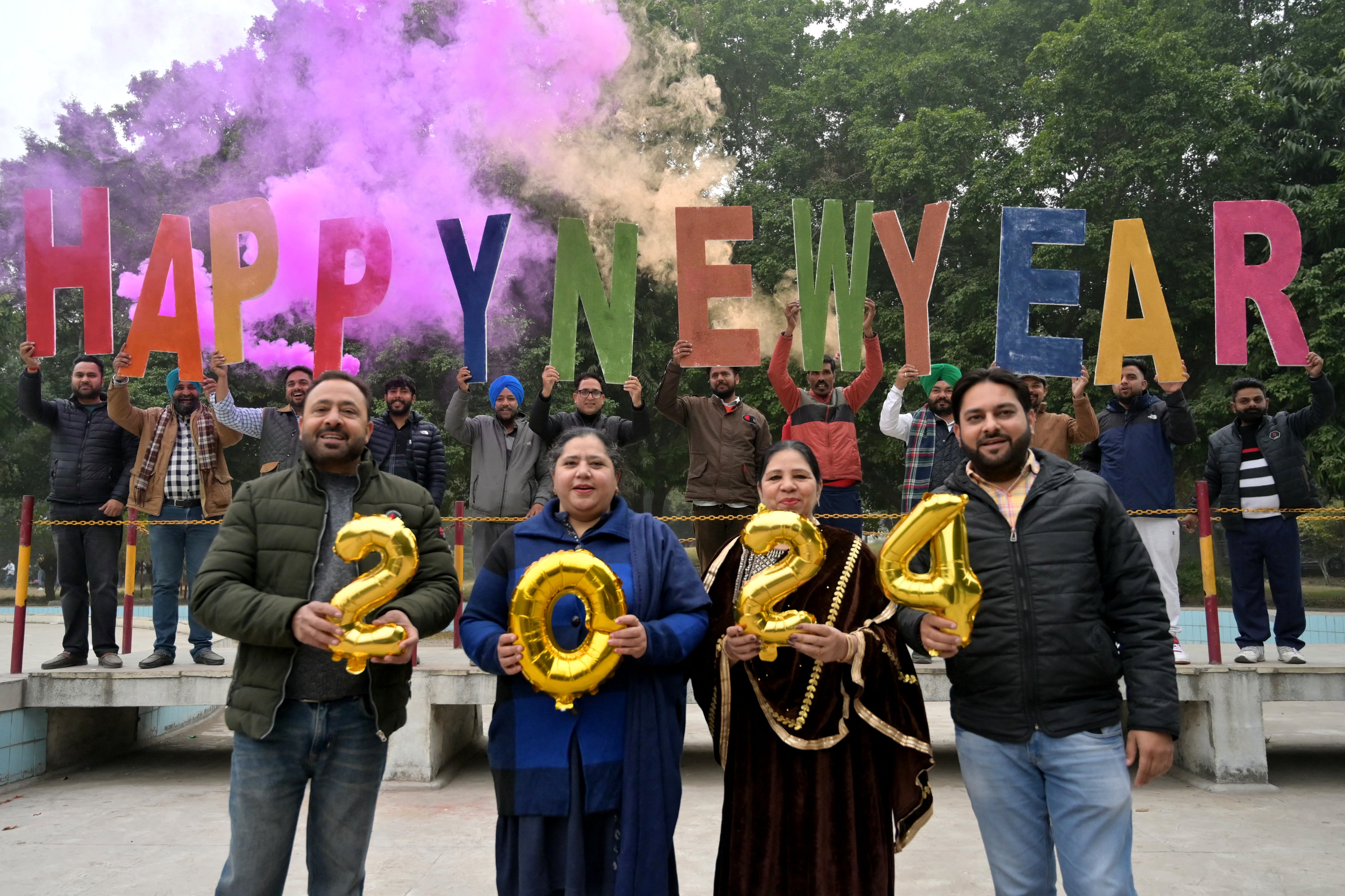 People holding 'Happy New Year' letters cutout pose for photos during New Year's Eve celebrations in Amritsar