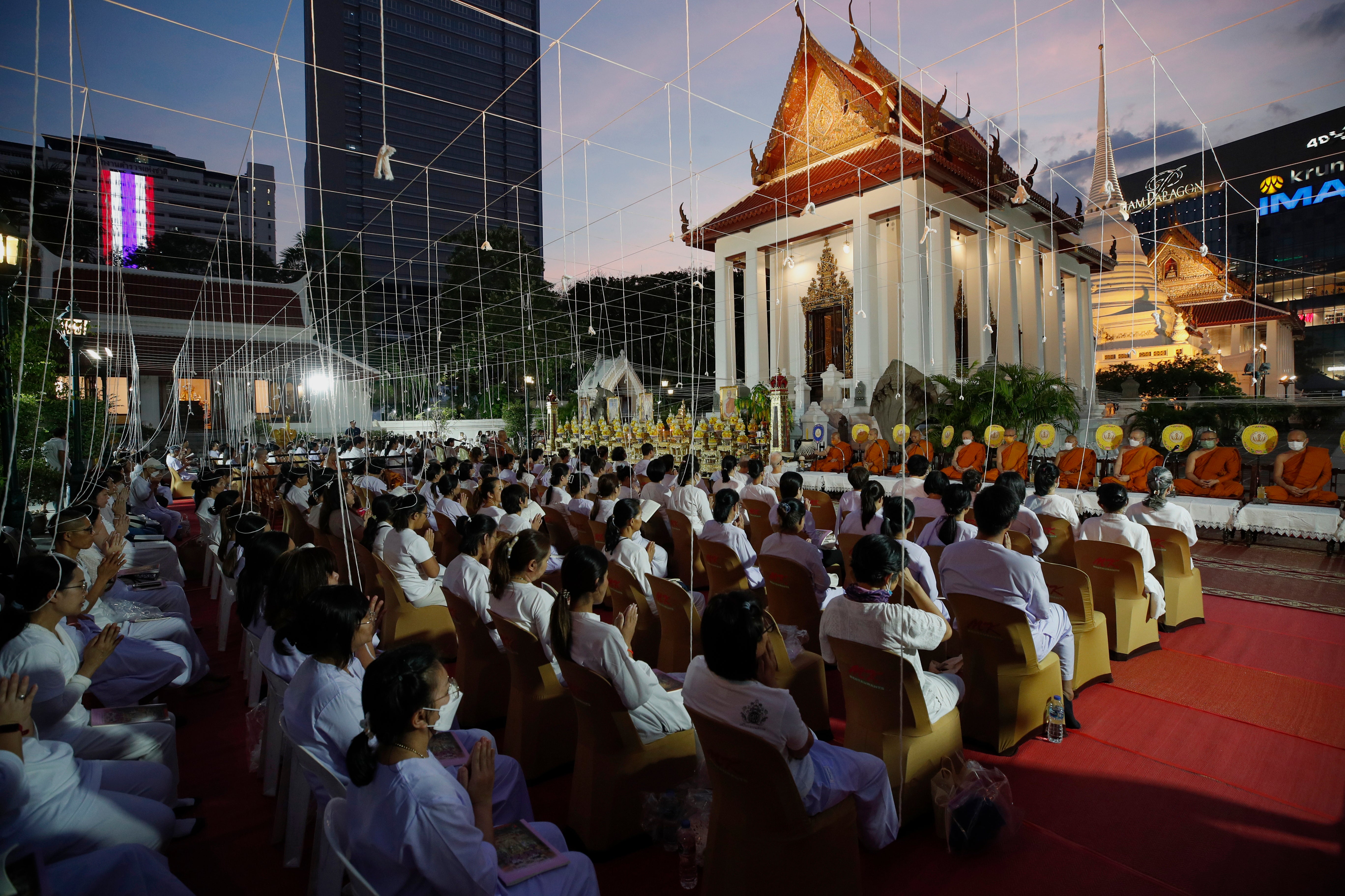 Thai people and Buddhist monks chant during a prayer rite at Wat Pathum Wanaram temple in Bangkok,