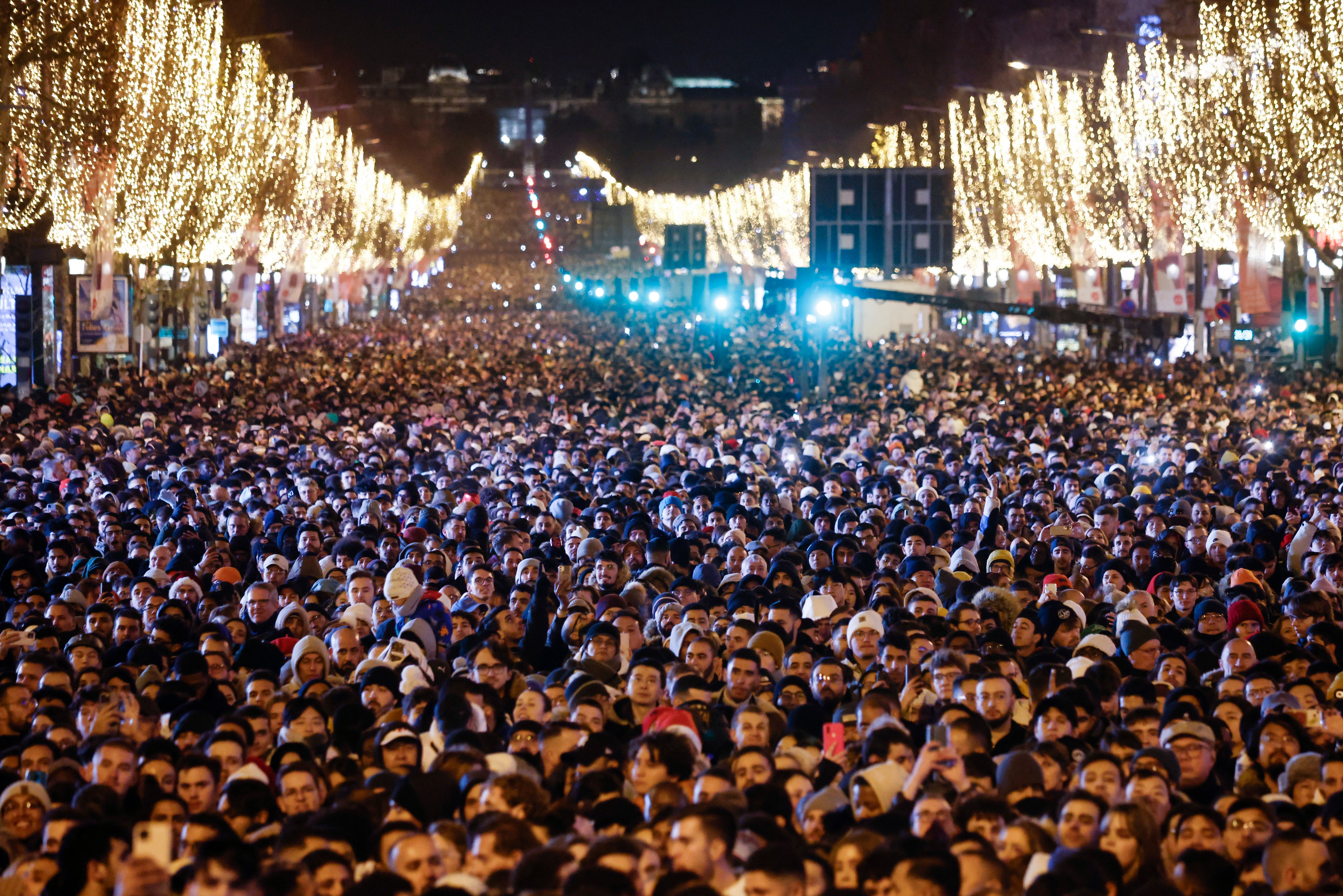 A large crowd gathers on the Champs Elysees to view a light show and fireworks near the Arc of Triomphe