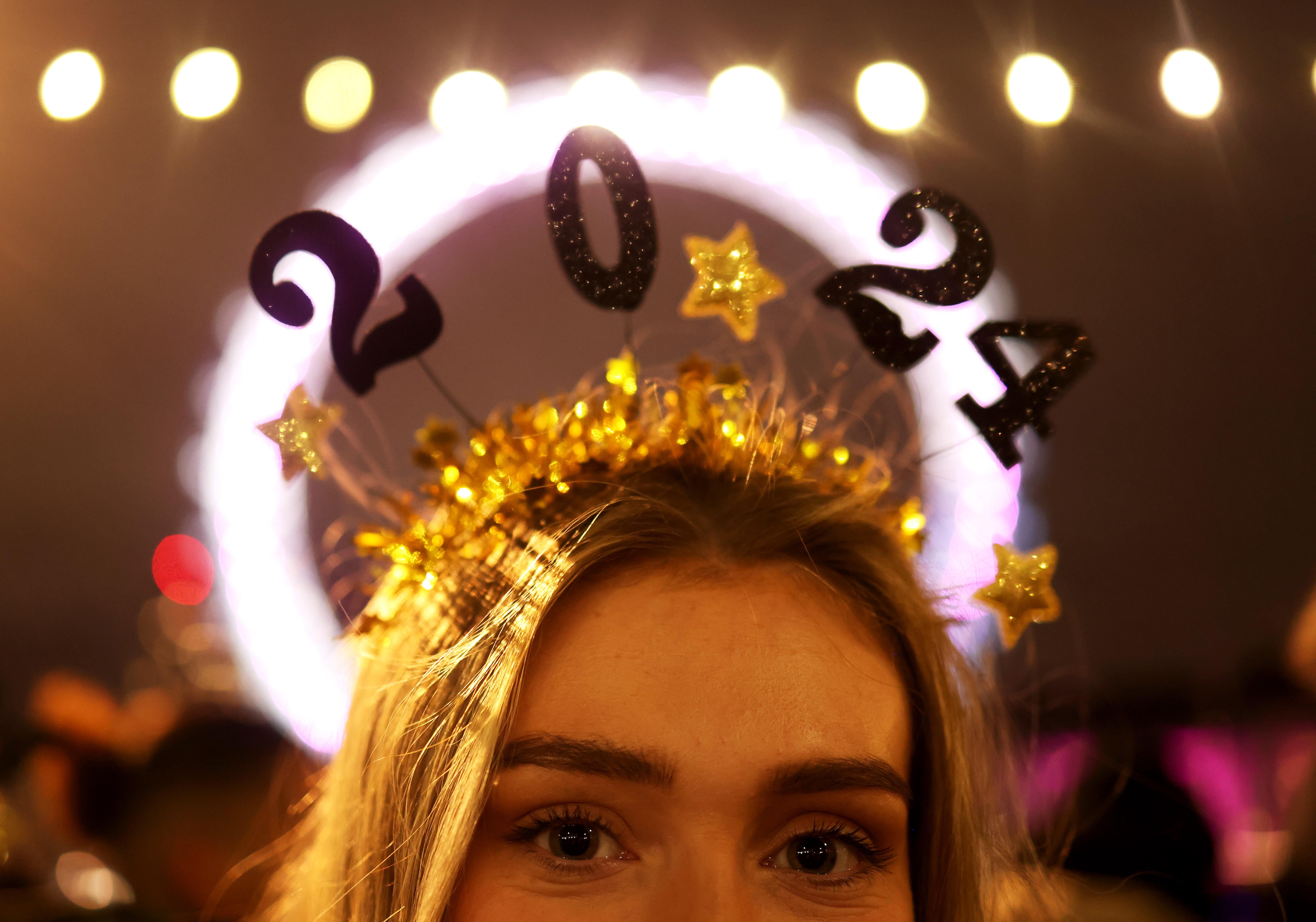 A reveller proudly shows off a 2024 headband ahead of the firework display