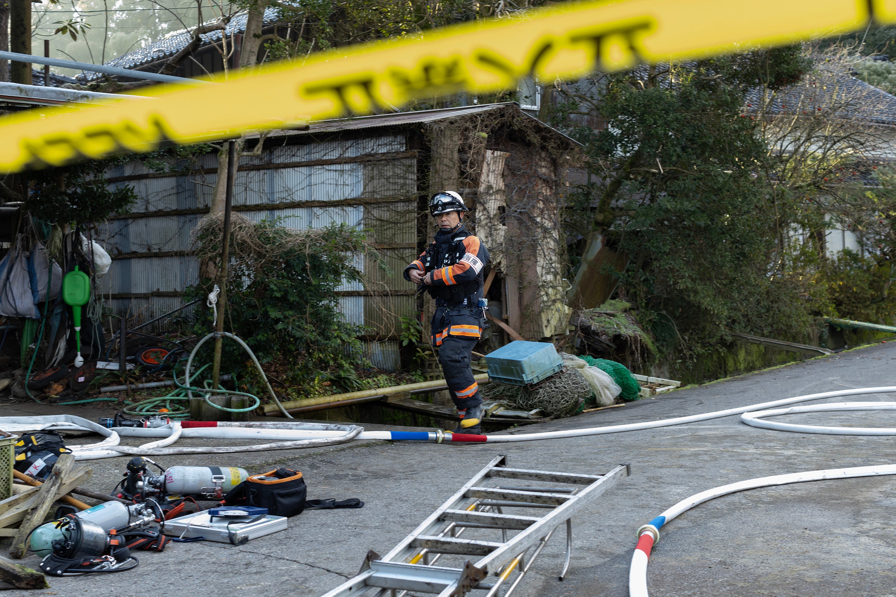 Firefighters investigate a partly burned and collapsed house