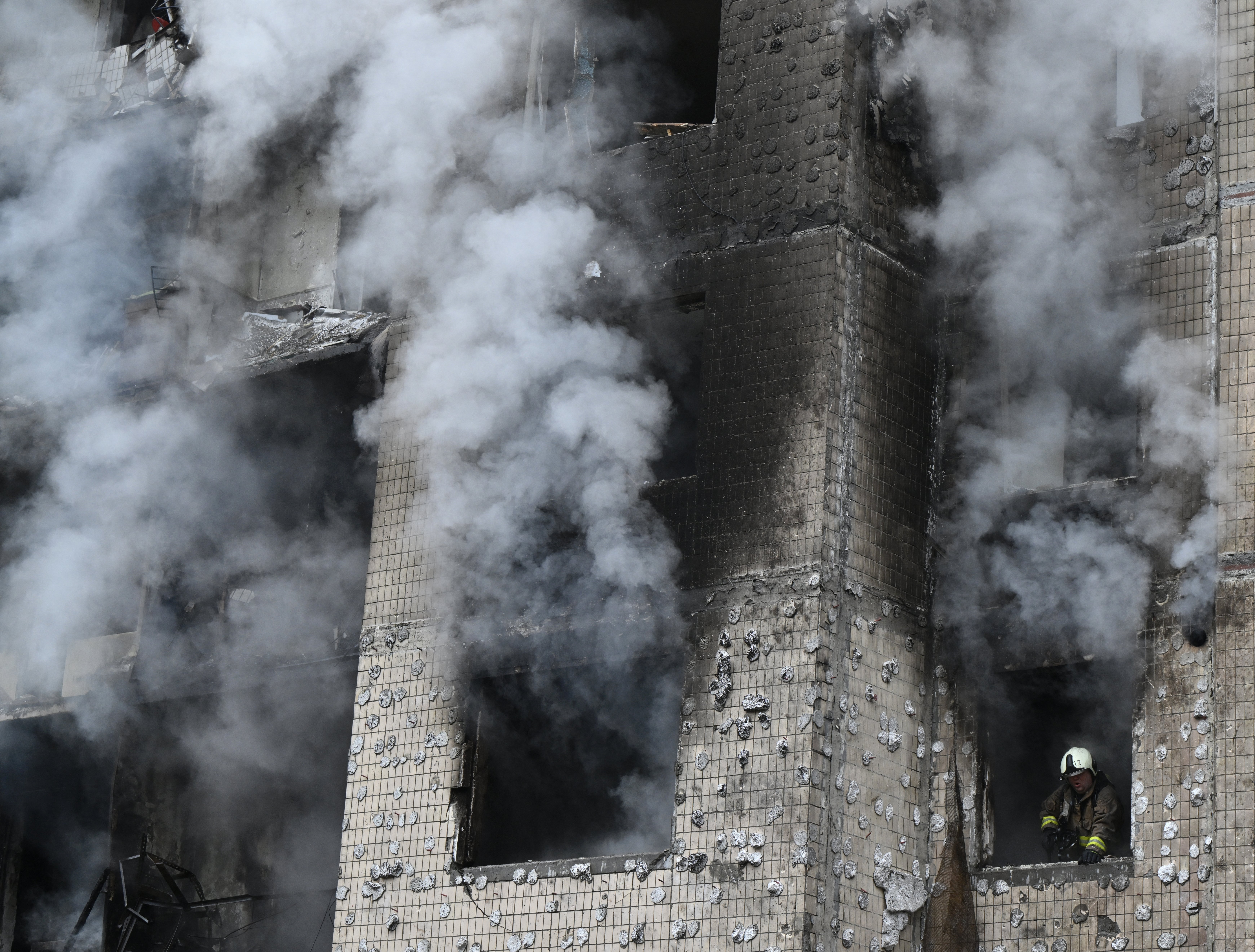 A firefighter looks out of a window as he works in a residential building destroyed by a missile attack in central Kyiv