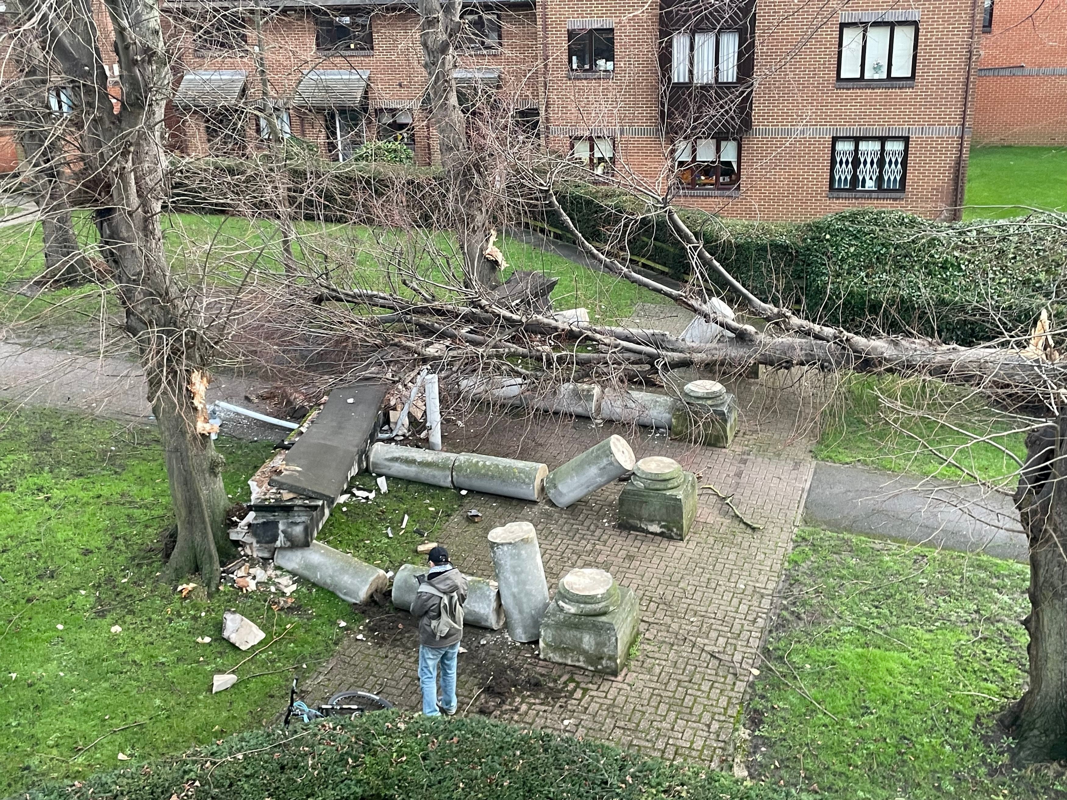 A tree blown over by the wind crashes into a portico, knocking it down in Tooting, southwest London