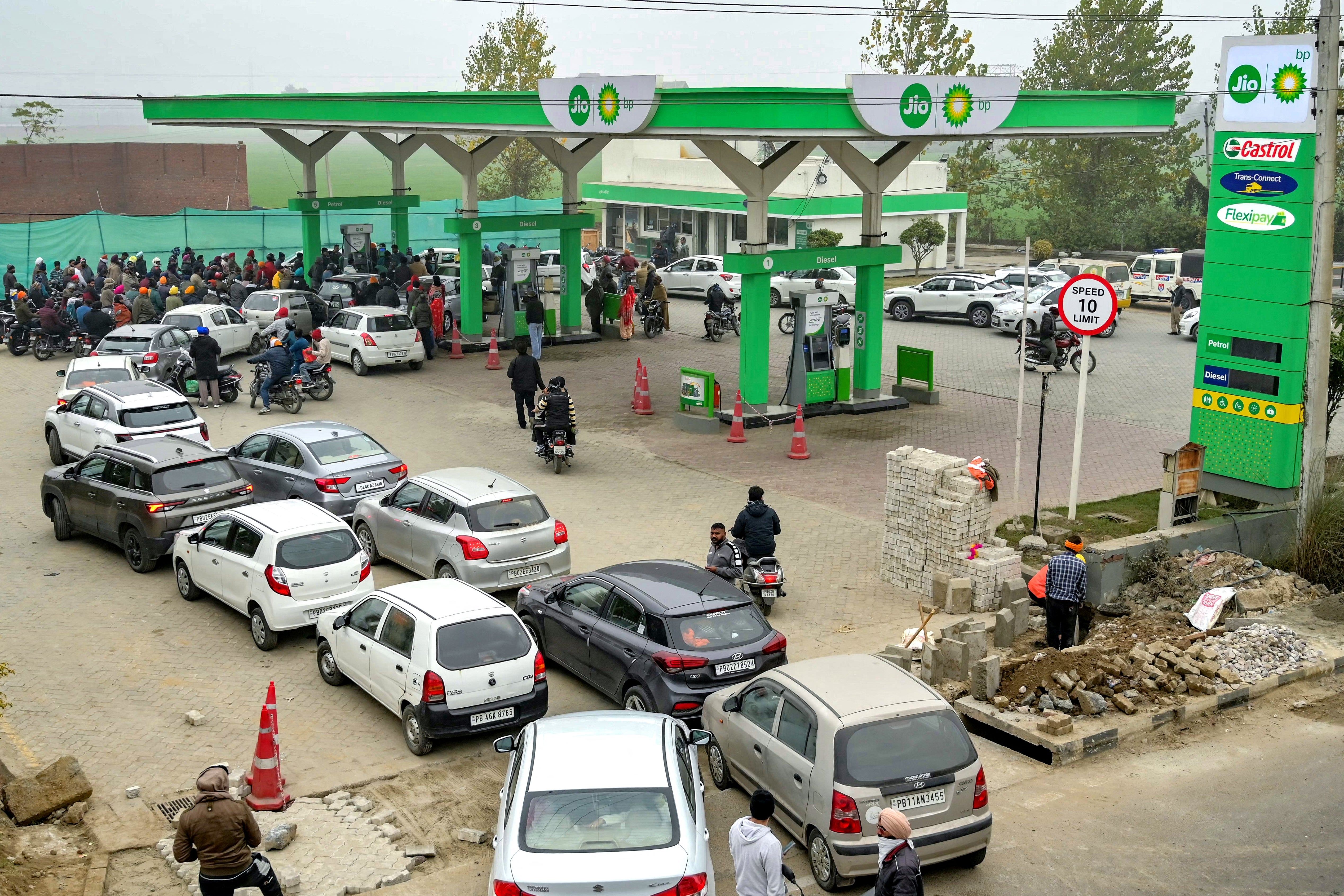 People with their vehicles wait in queues to refill fuel tanks at a fuel station in Amritsar on 2 January