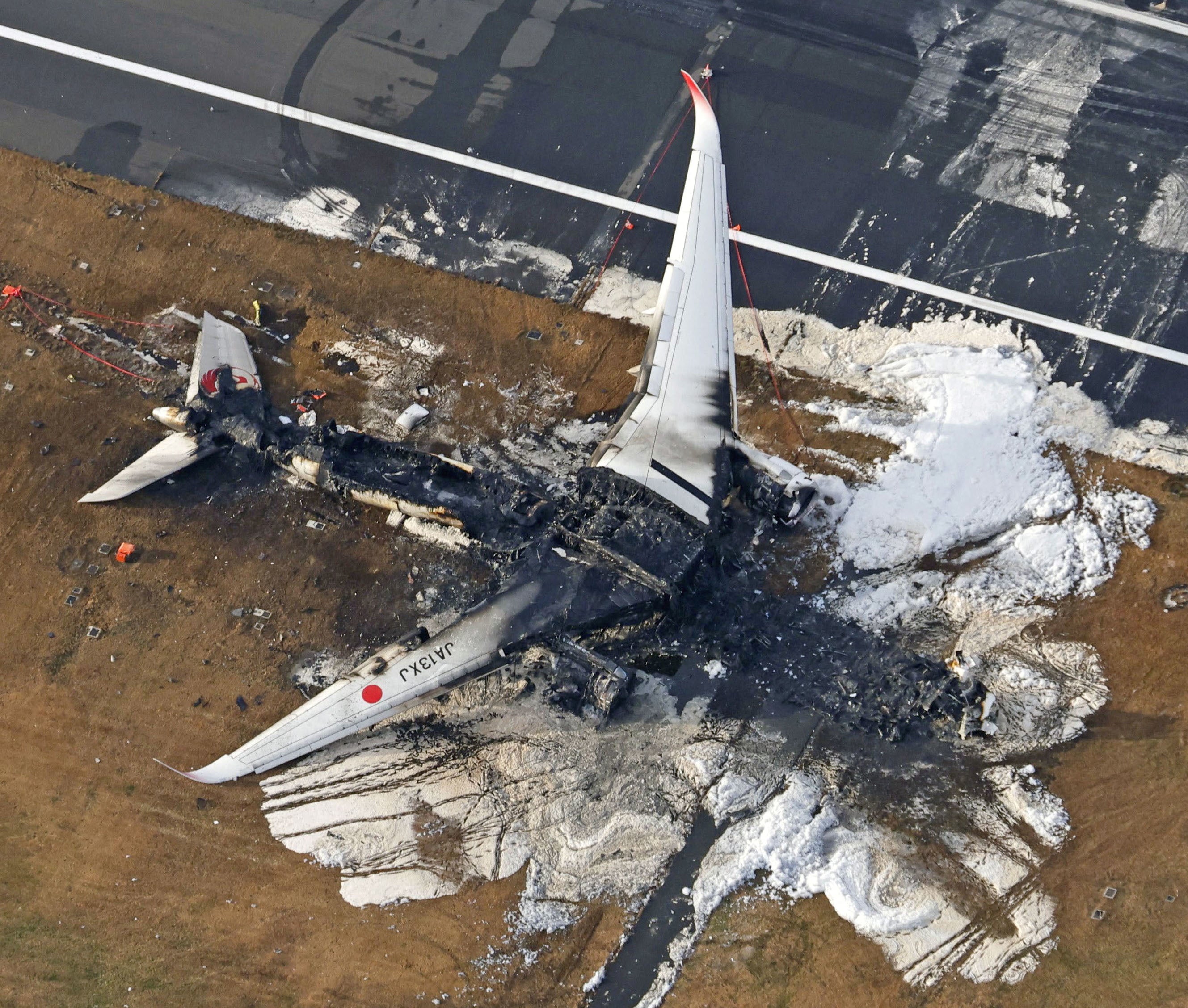 An aerial view shows burnt Japan Airlines’ (JAL) Airbus A350 plane after a collision with a Japan Coast Guard aircraft at Haneda International Airport in Tokyo