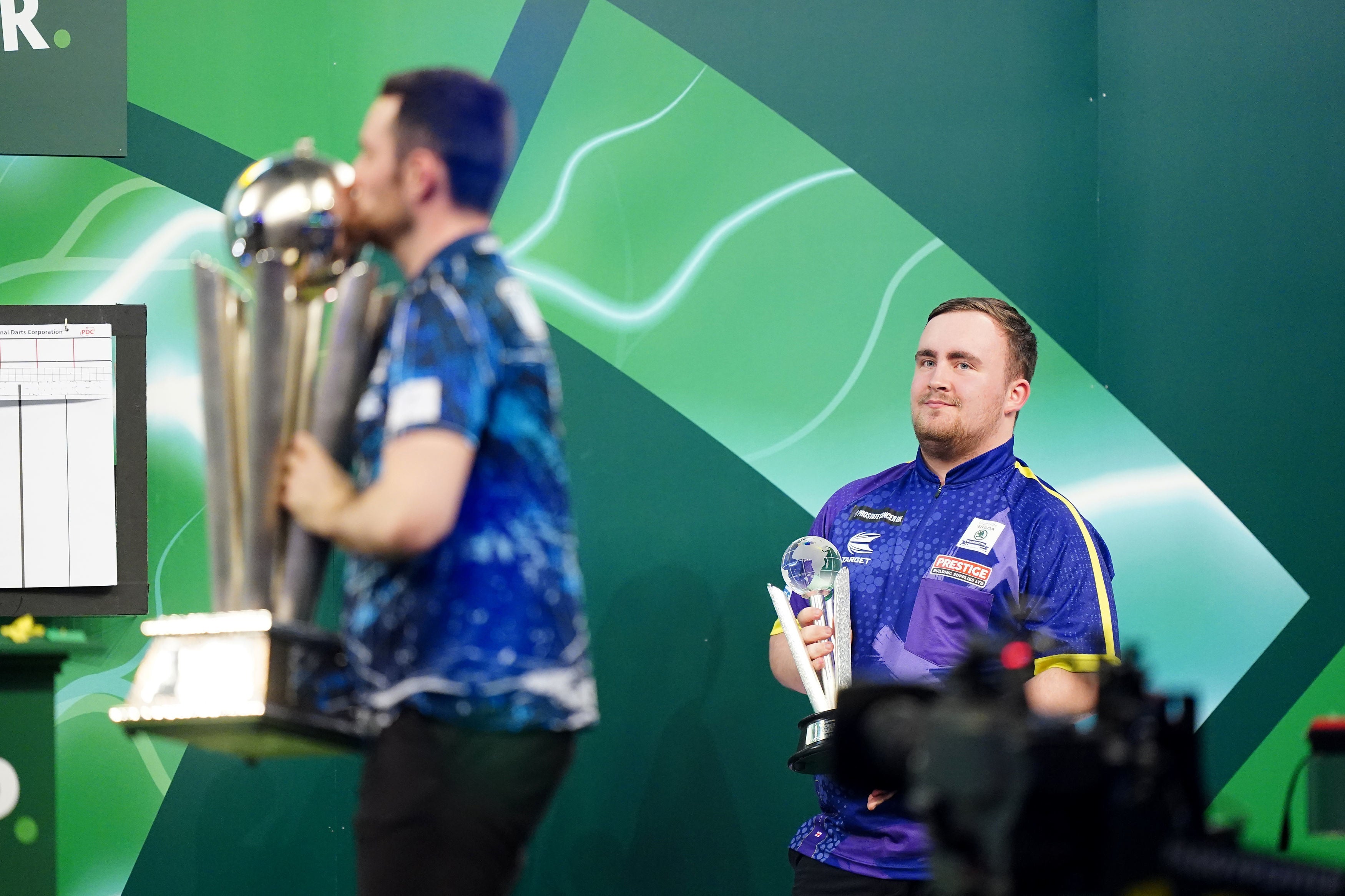 Littler looks on as Luke Humphries celebrates with the trophy