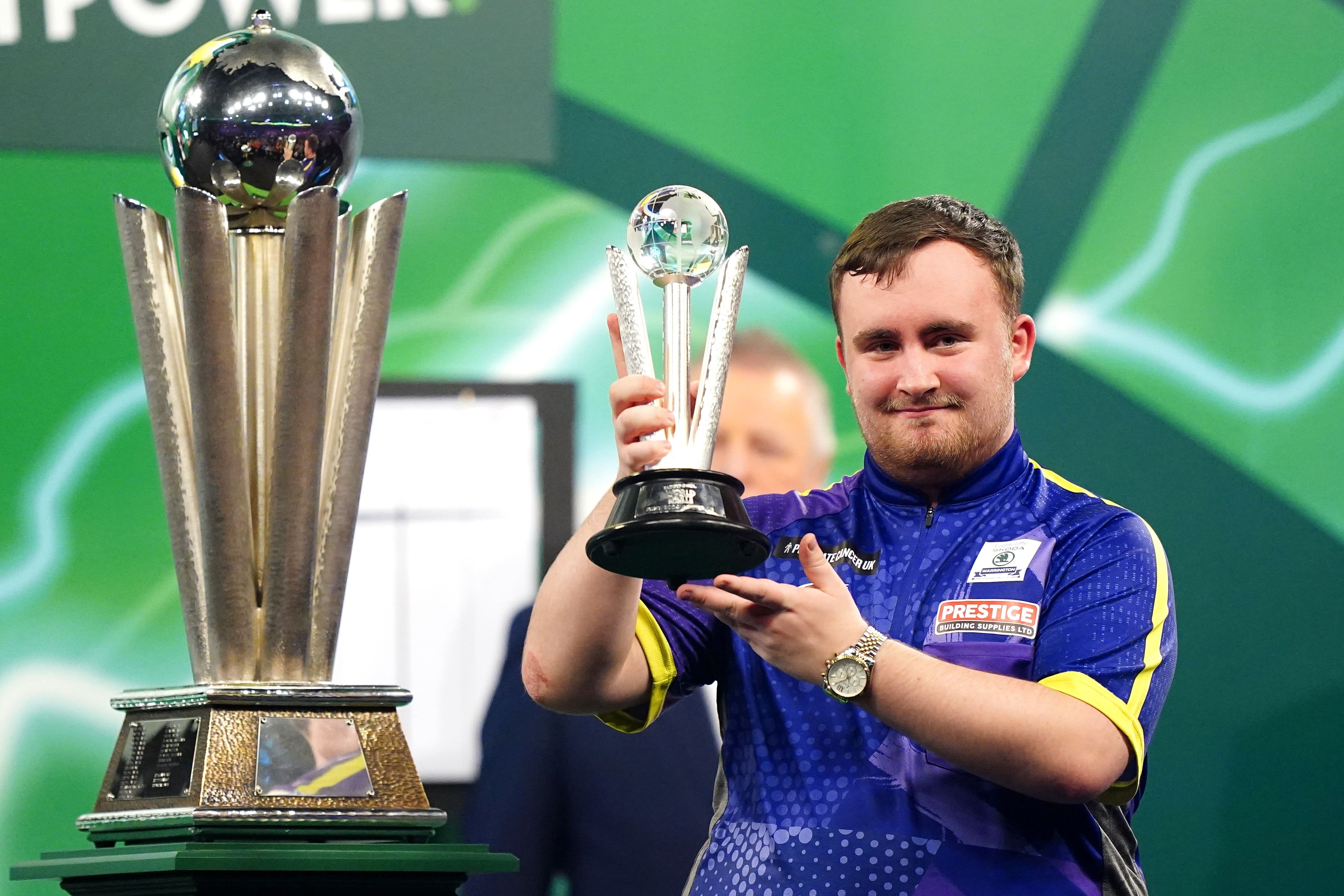 Luke Littler lifts his runner-up trophy after the World Championship final (Zac Goodwin/PA)