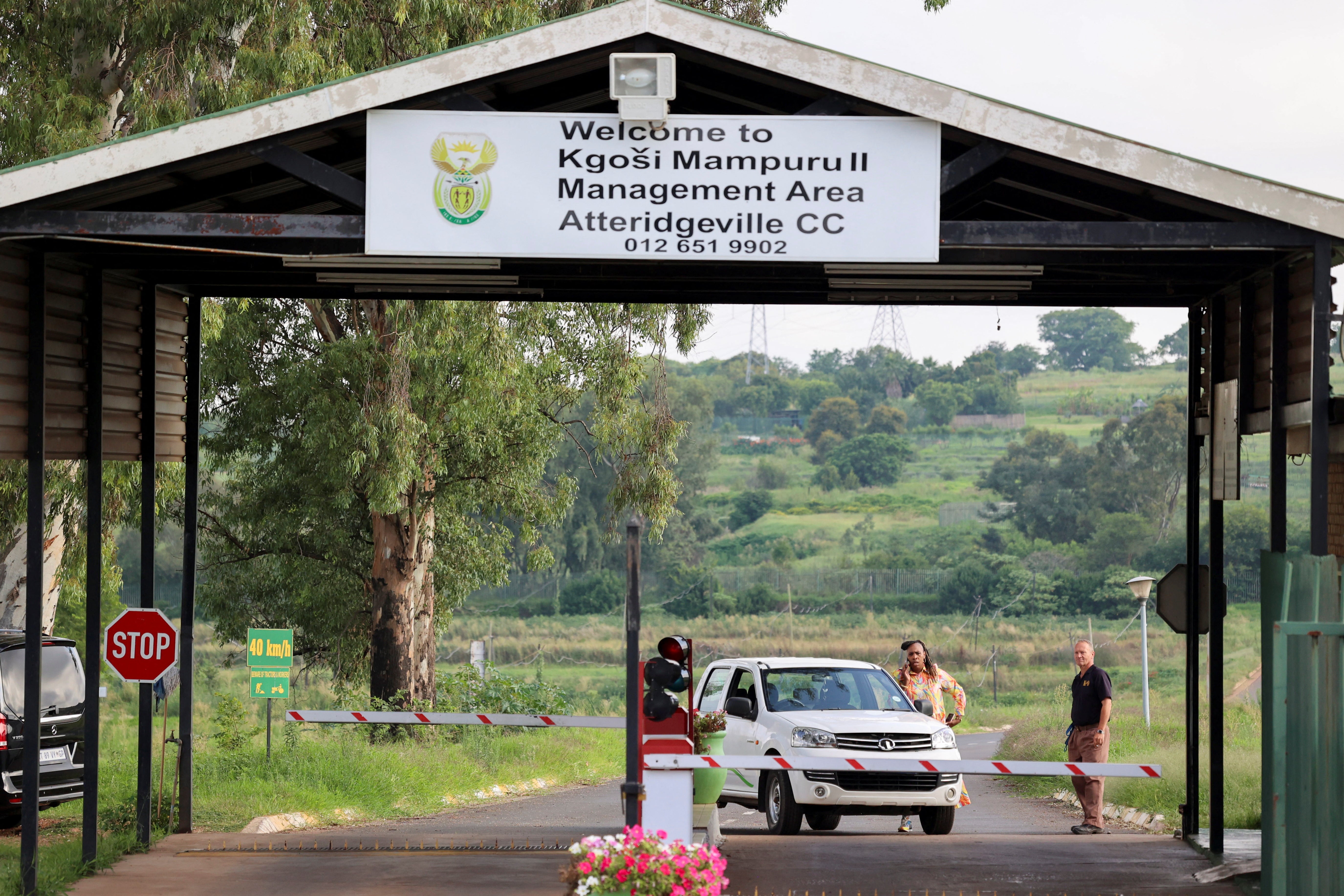 A person speaks on the phone next to a car at the entrance of the Atteridgeville Correctional Centre, where South African athlete Oscar Pistorius, convicted of killing his girlfriend Reeva Steenkamp in 2013, is due to be released on parole, in Pretoria, South Africa