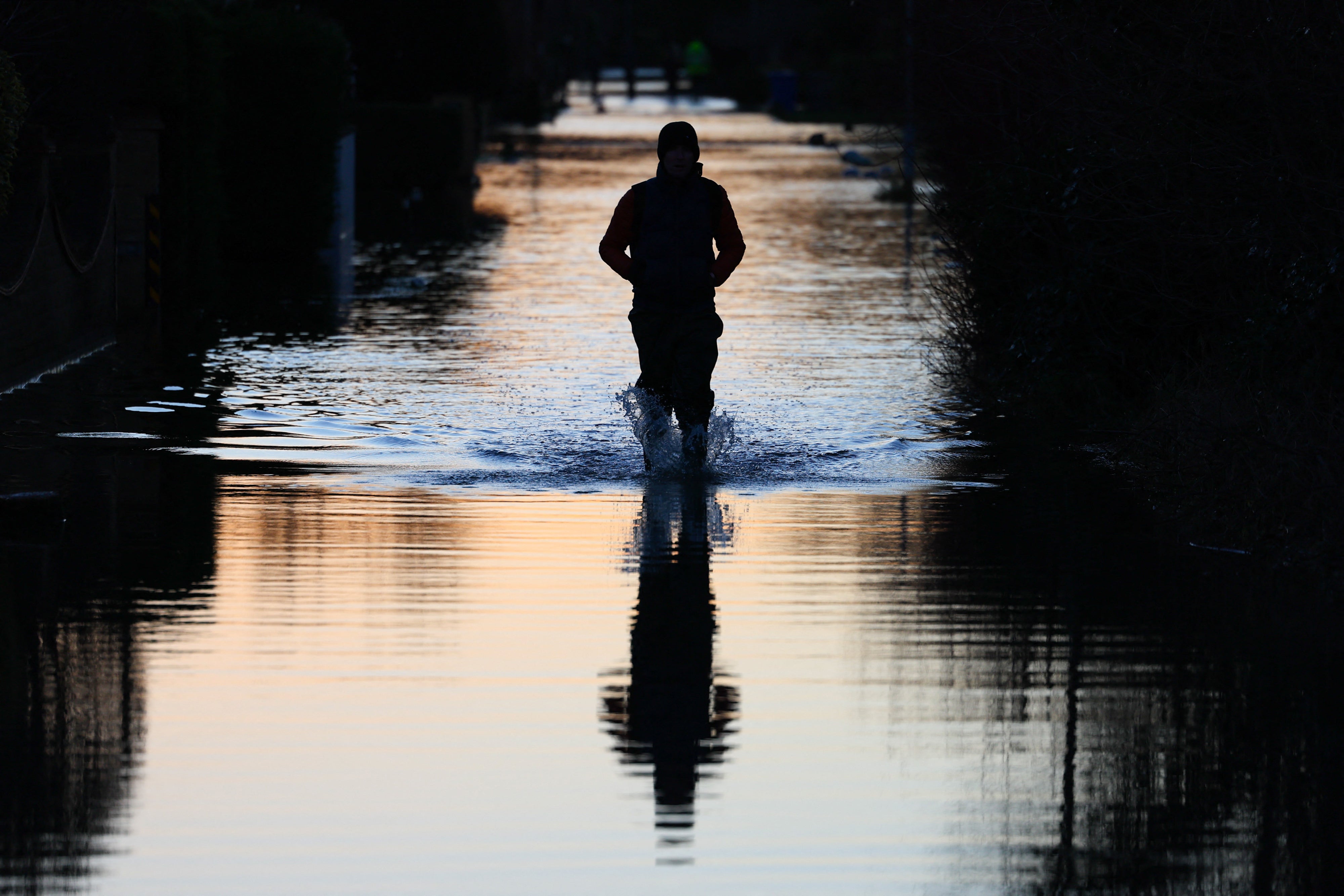 People walk through floodwater on a flooded street in Wraysbury, west of London on January 9, 2024