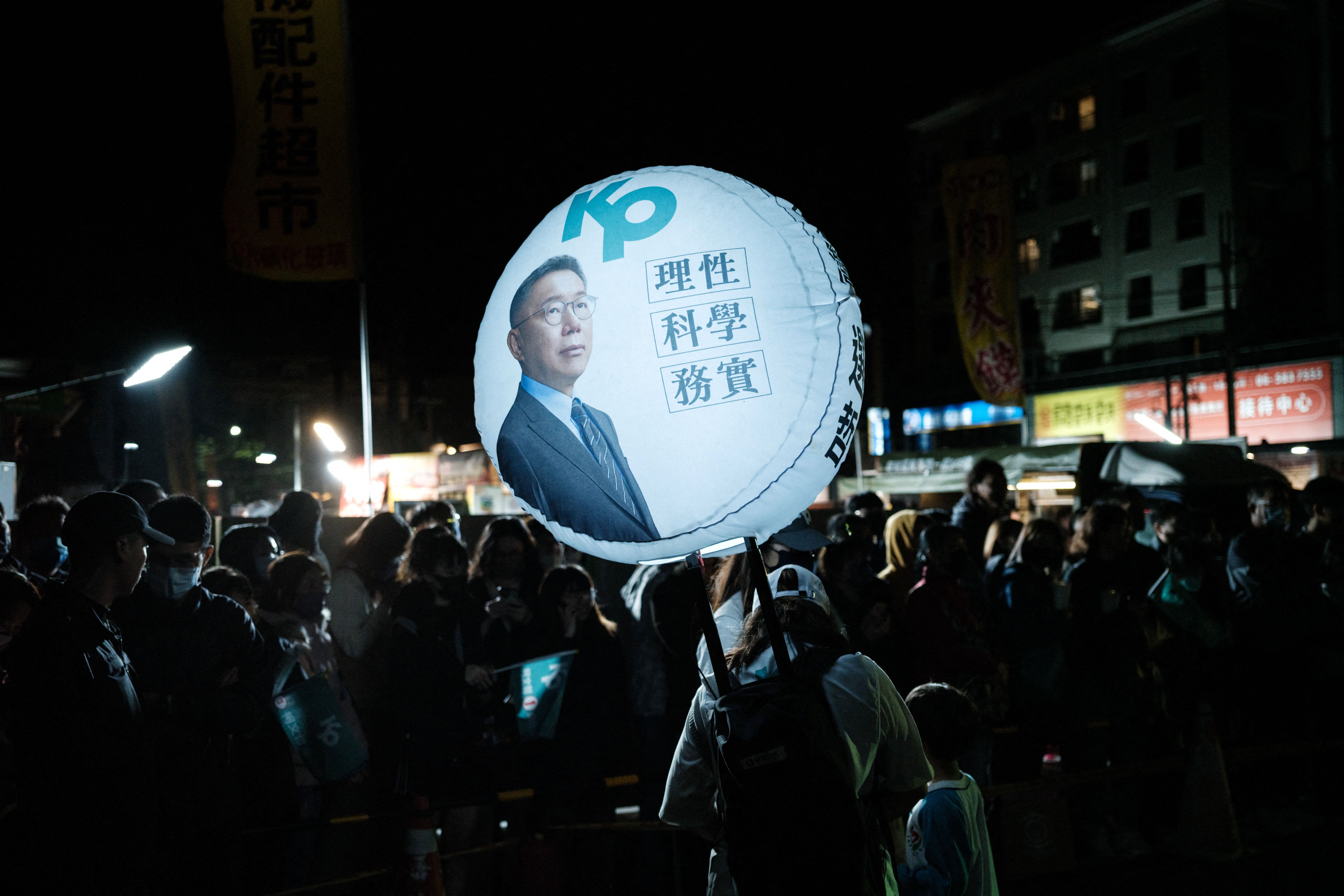 A woman carries a balloon with the portrait of the Taiwan People’s Party (TPP) presidential candidate Ko Wen-je