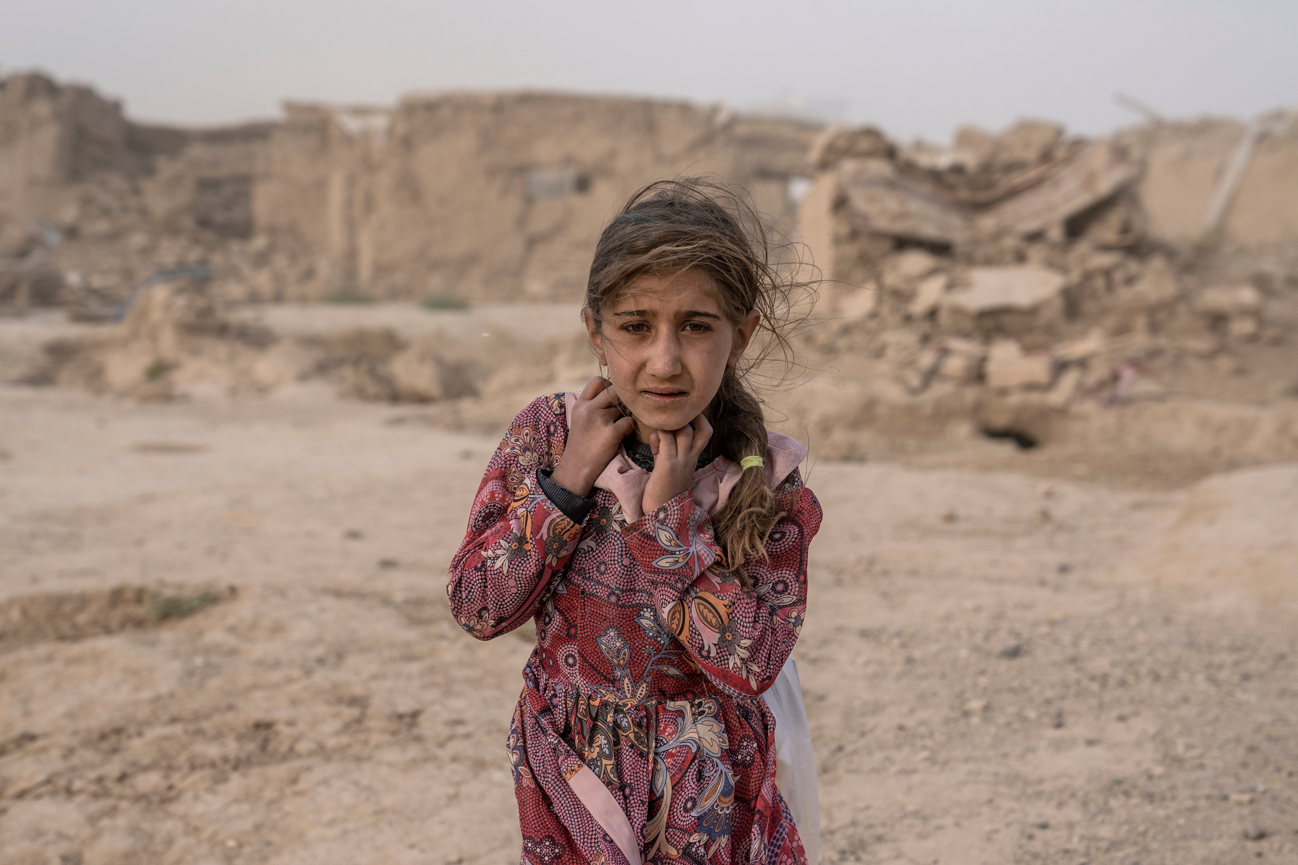 An Afghan girl carries donated aid to her tent, while she is scared from the fierce sandstorm, after an earthquake