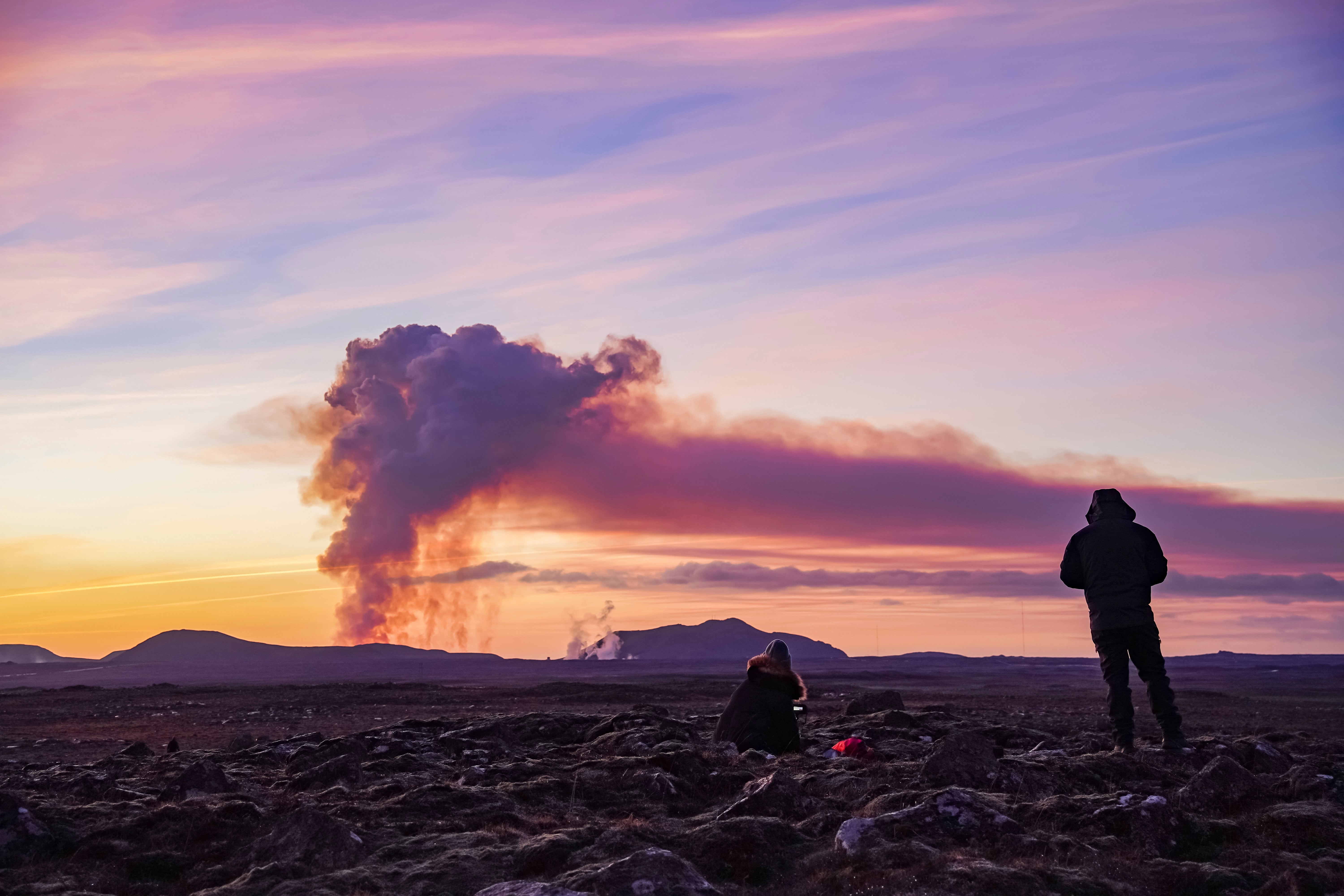 People watch from the north as the volcano erupts near Grindavík, Iceland, on Sunday