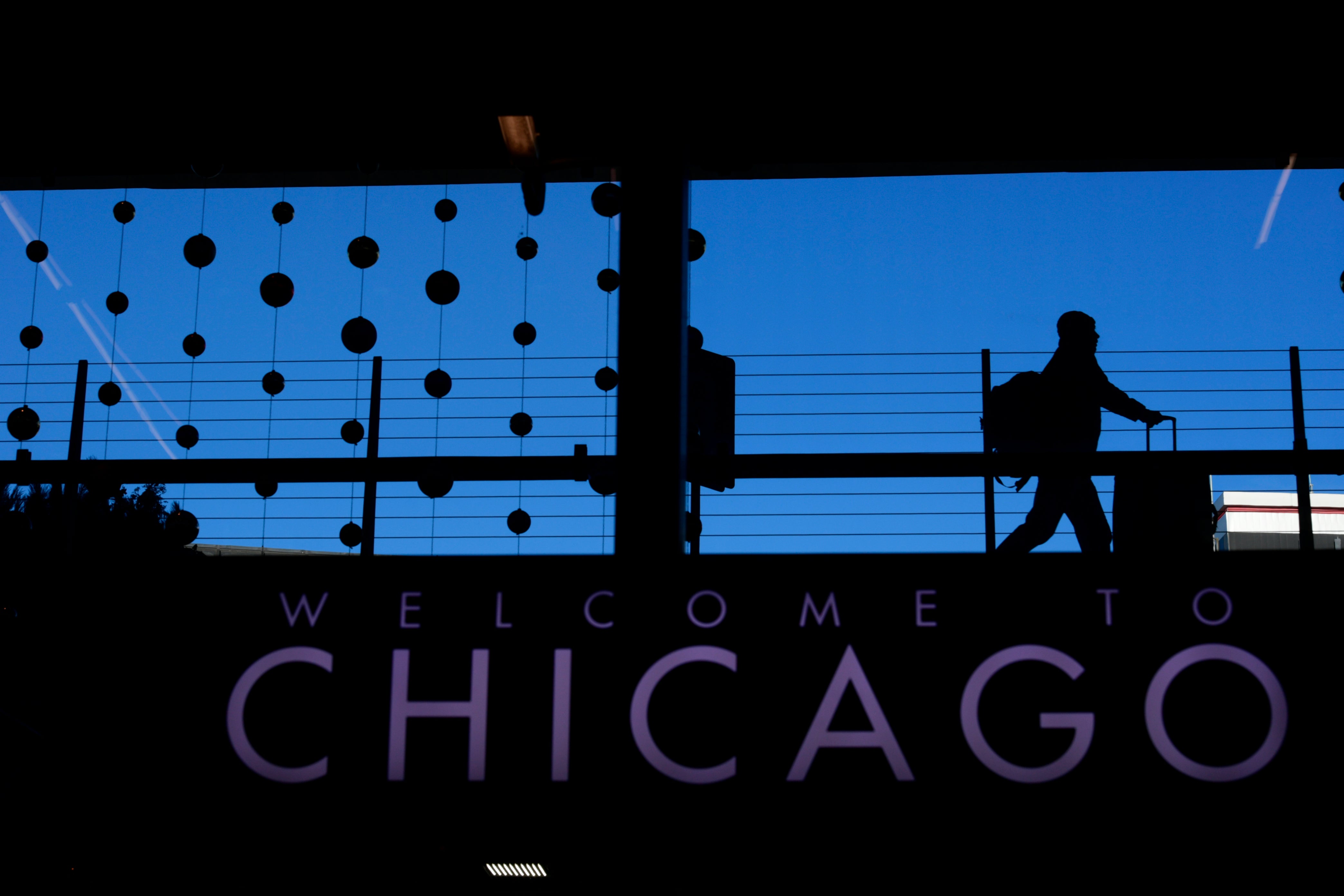 A passenger walks with luggage past holiday decorations at Chicago O'Hare International Airport. A woman died after she became trapped in a luggage conveyor belt at the airport