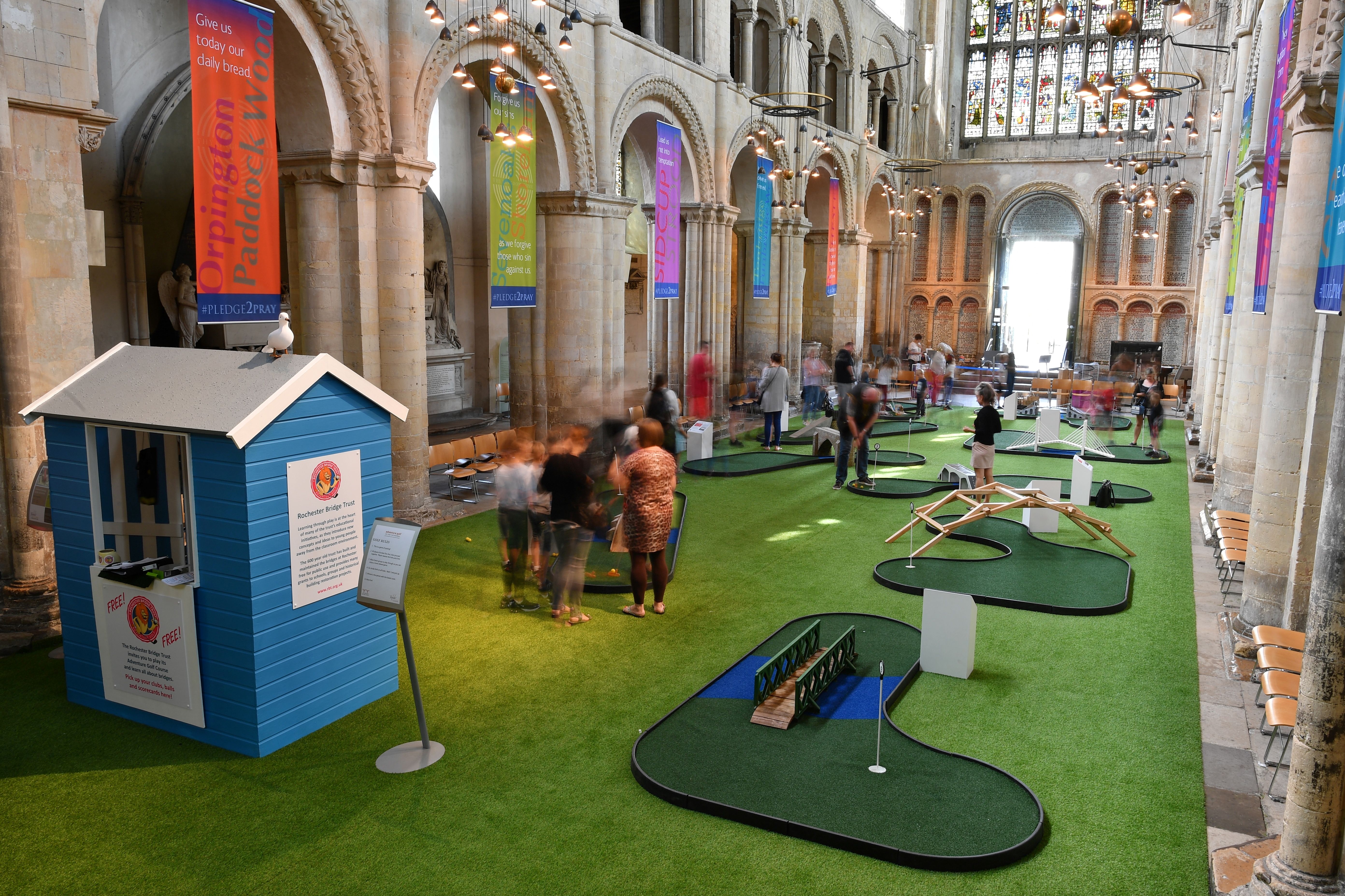 People play on a bridge-themed mini-golf course set up in the nave of Rochester Cathedral