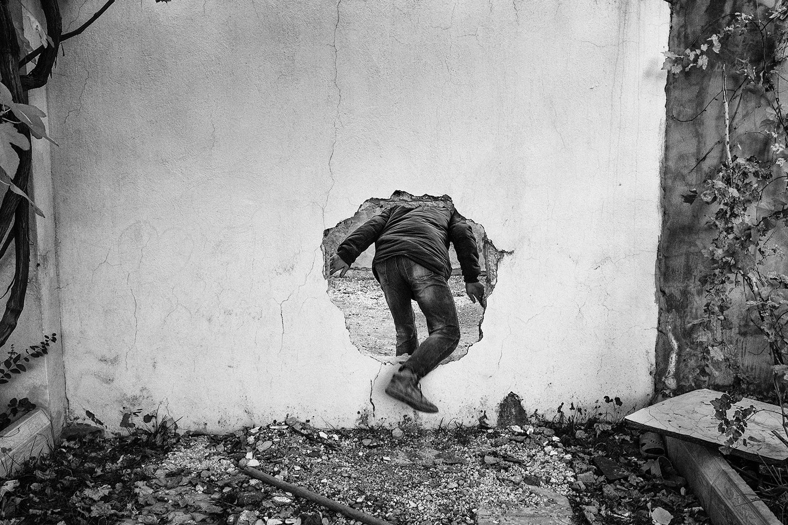 A member of the PKK linked Civilian Protection Unit uses a hole in a wall to cross a street controlled by Turkish special military forces in Nusaybin in 2015