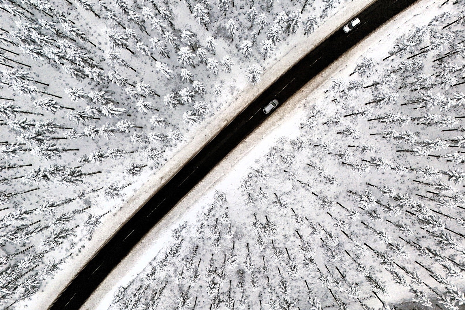 An aerial view shows cars on a road crossing the snow-covered landscape at the Kahler Asten mountain near Winterberg, western Germany on 1 December, 2023