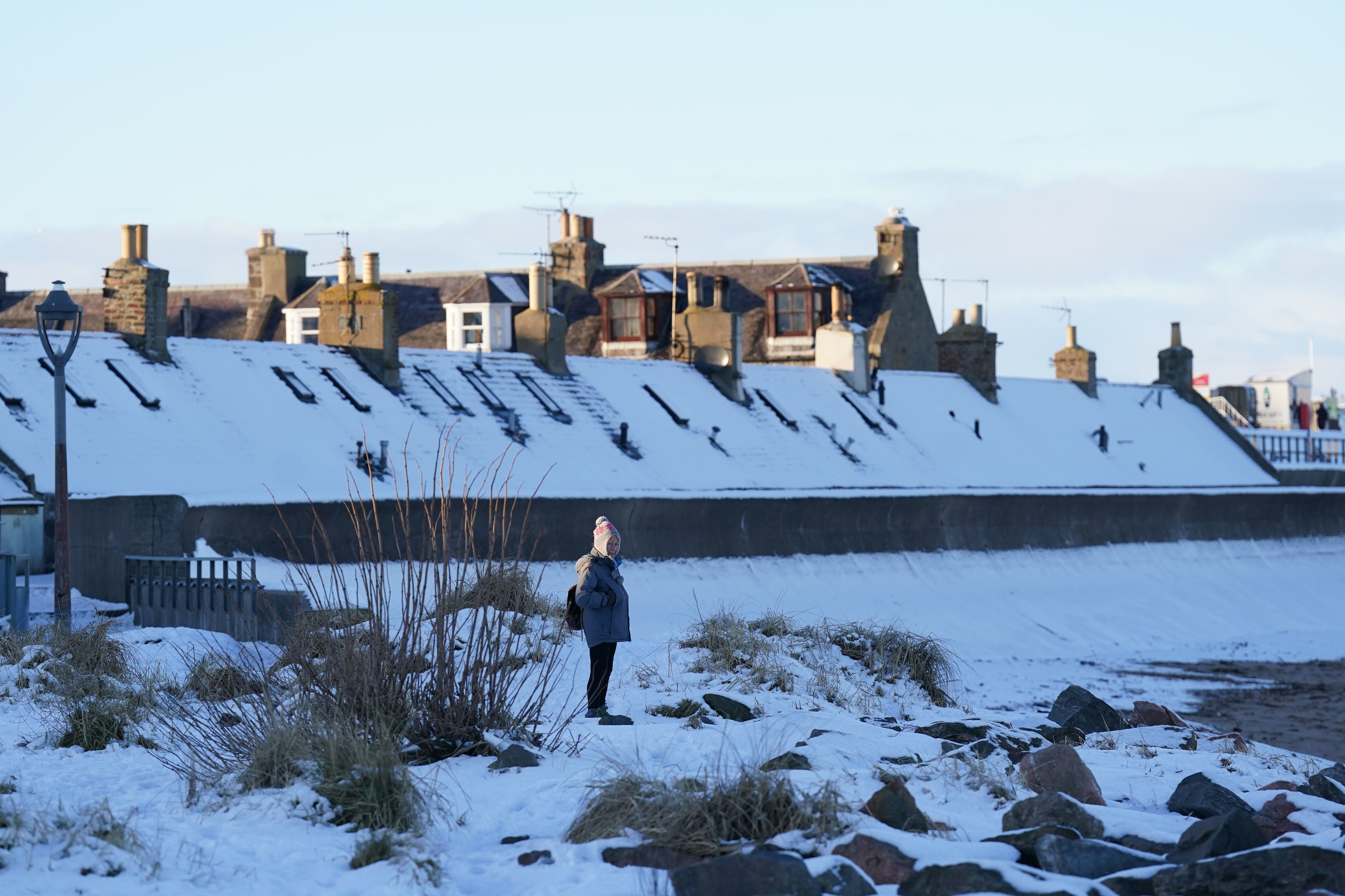 A person looks out from a snow-covered beach front in Aberdeen