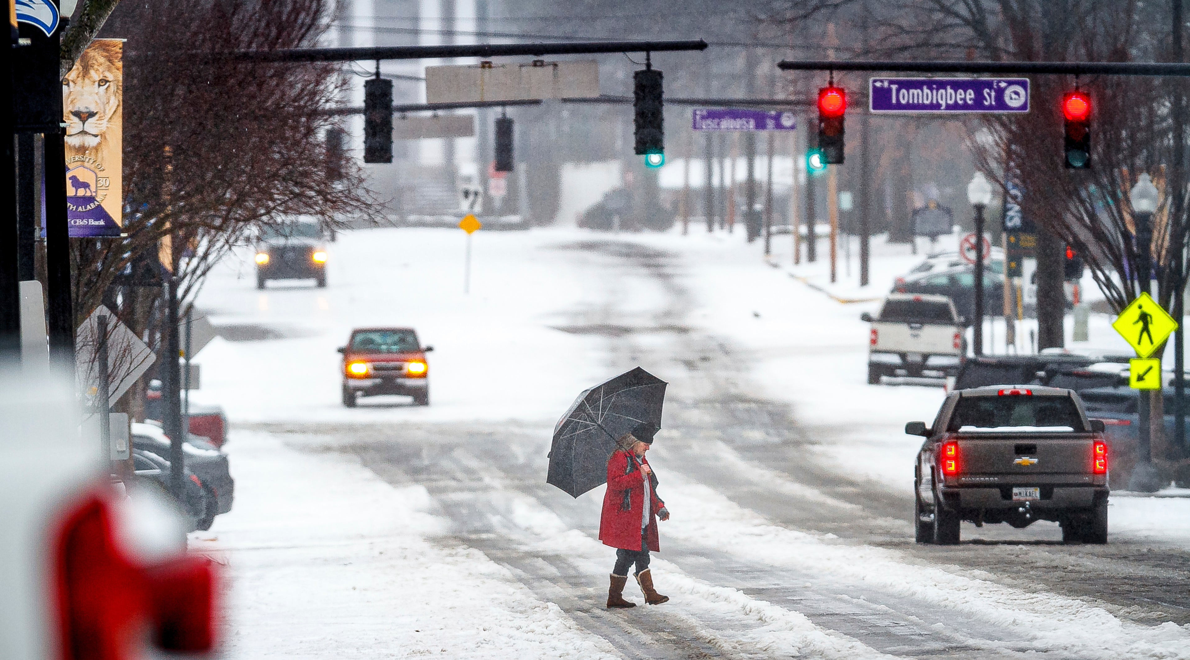 A man crosses North Pine Street as motorists navigate an ice and snow covered road, Thursday, Jan. 18, 2024 in downtown Florence, Ala.. (Dan Busey/The TimesDaily via AP)