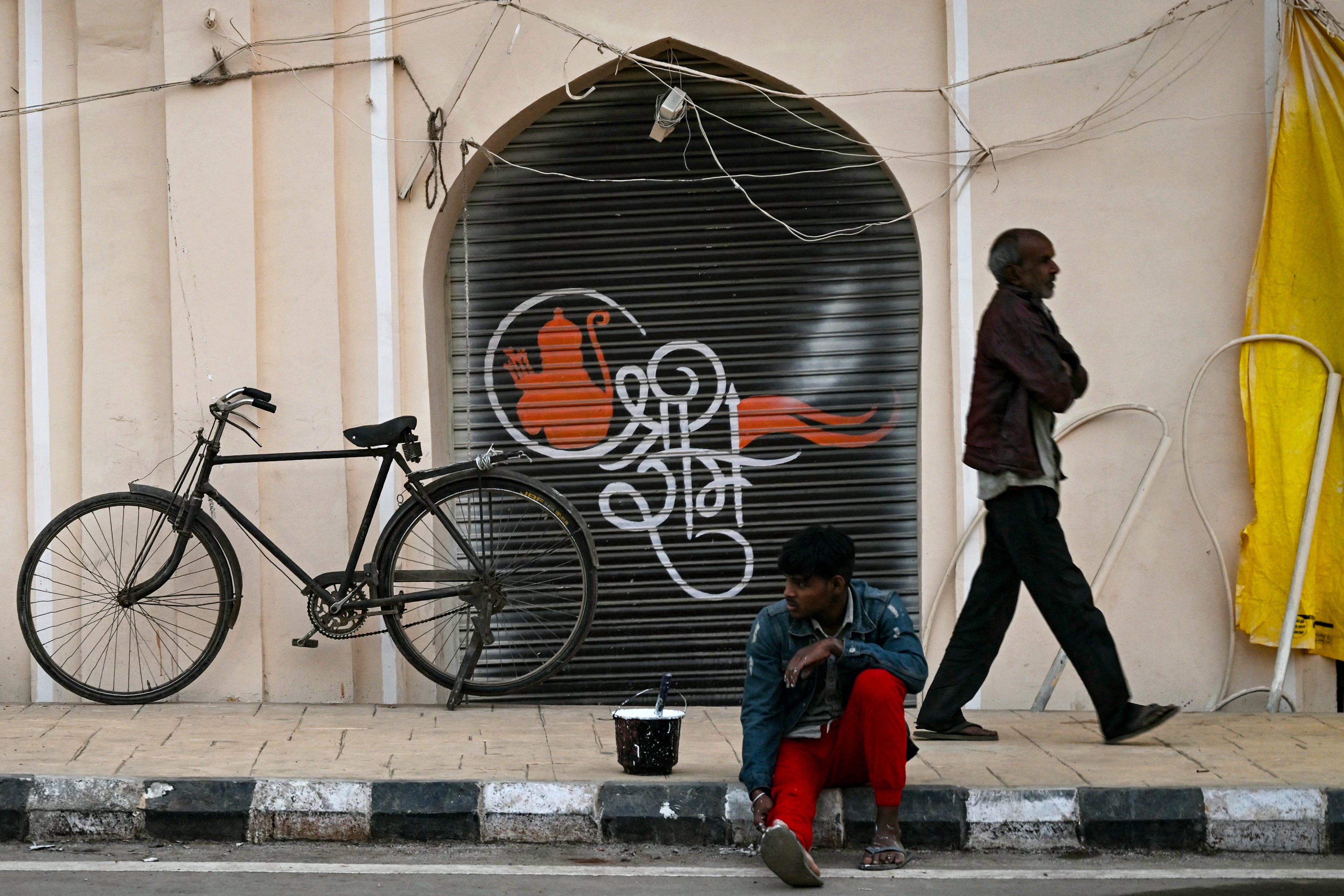 A worker rests opposite artwork depicting Ram – some Muslims claim that the government is only targeting the development of one community