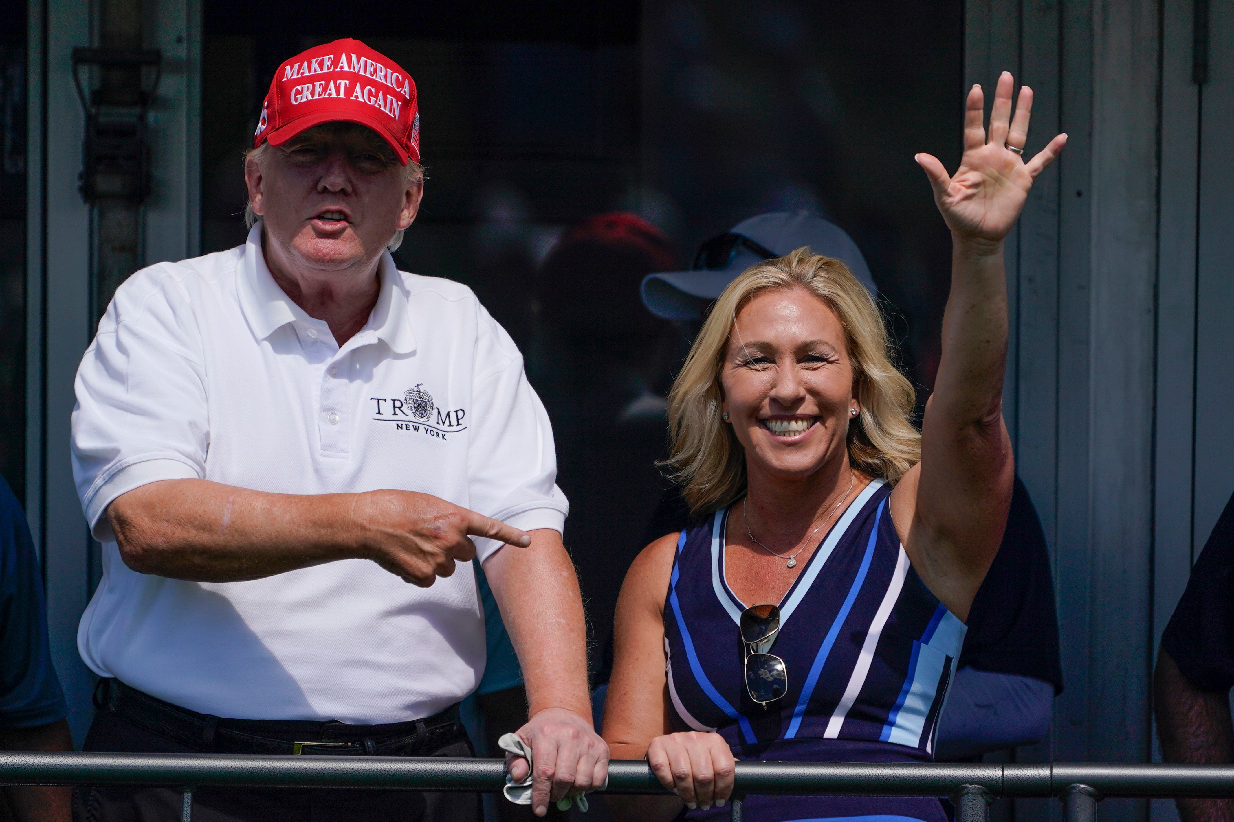 Rep. Marjorie Taylor Greene, R-Ga., waves while former President Donald Trump points to her while they look over the 16th tee during the second round of the Bedminster Invitational LIV Golf tournament, July 30, 2022, in Bedminster, N.J.