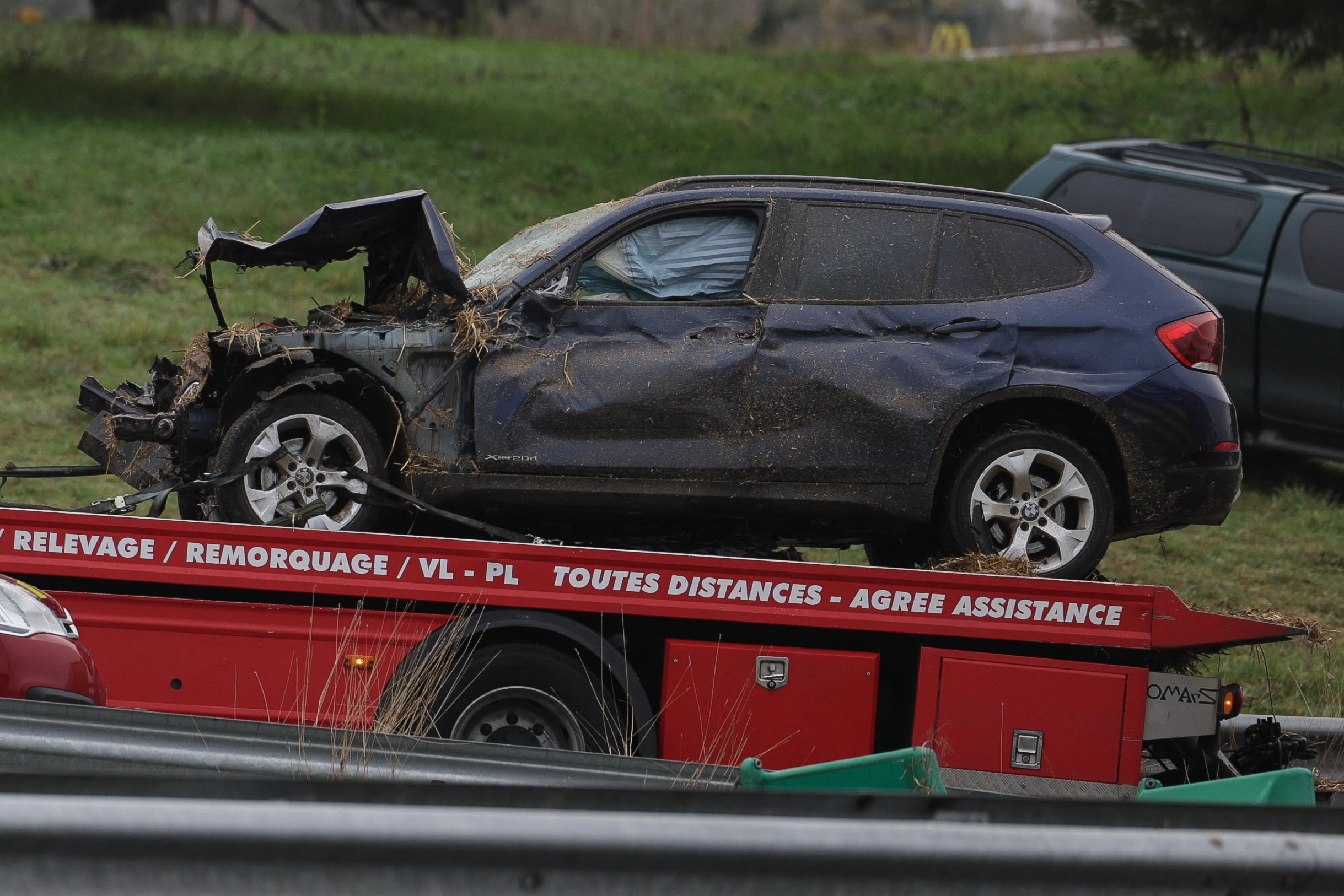 A flatbed truck removes the damaged vehicle which killed a woman and seriously injured her husband and teenage daughter