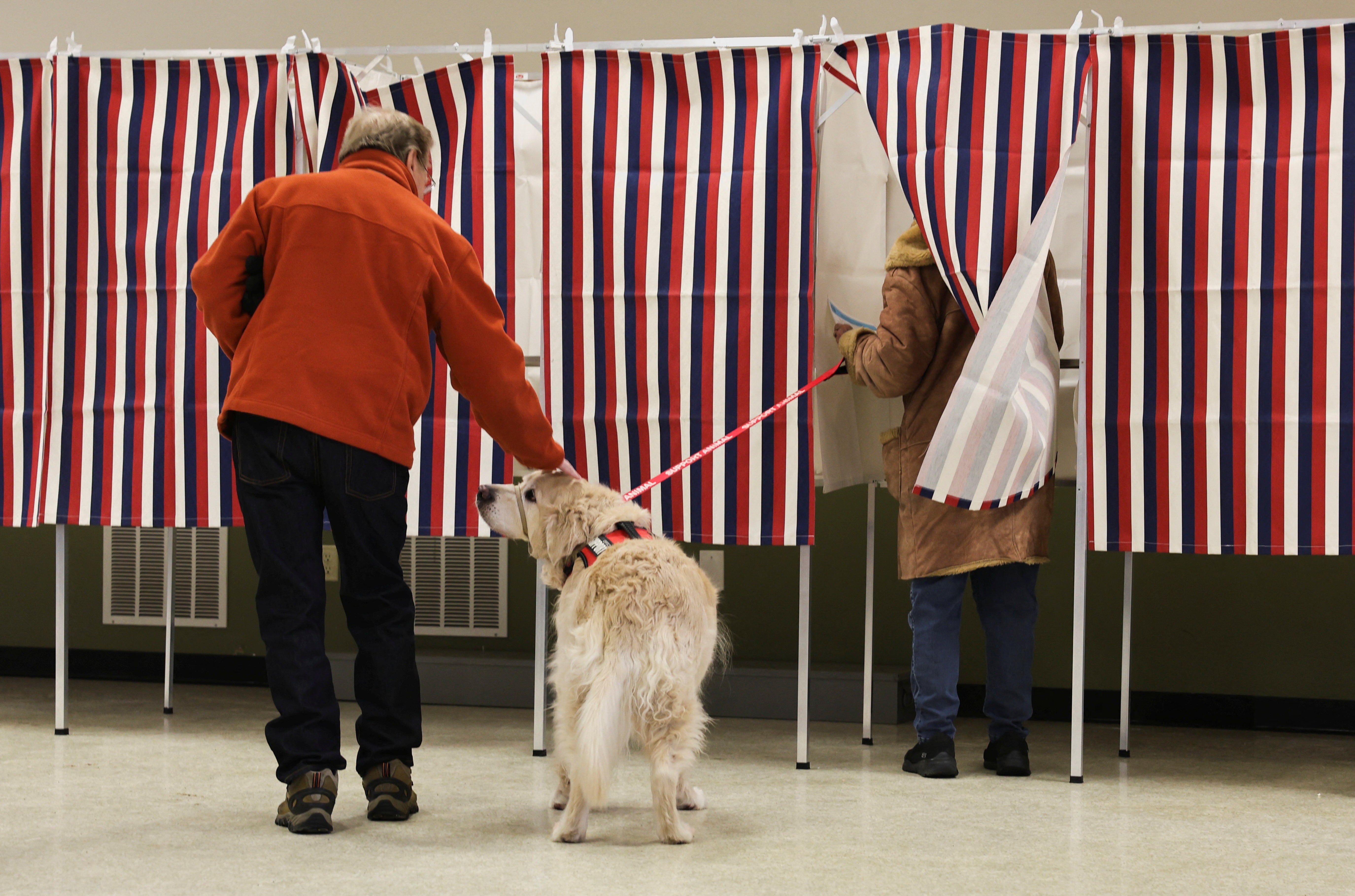 Phil Stokel pets Finn as dog owner Jean Palmer votes at Christ the King Parish