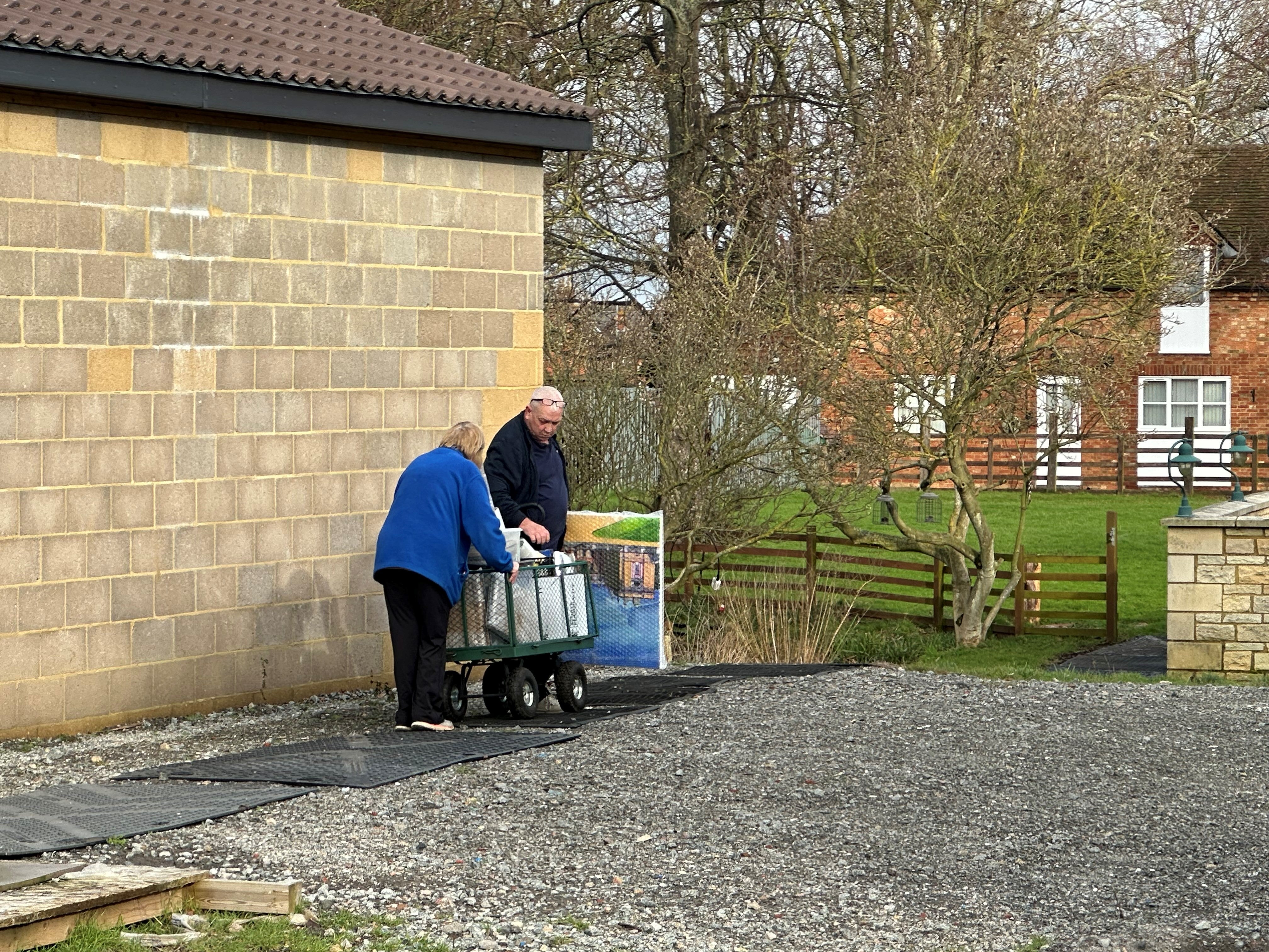 Items were taken away on a trolley from the building toward a van in the driveway at the house