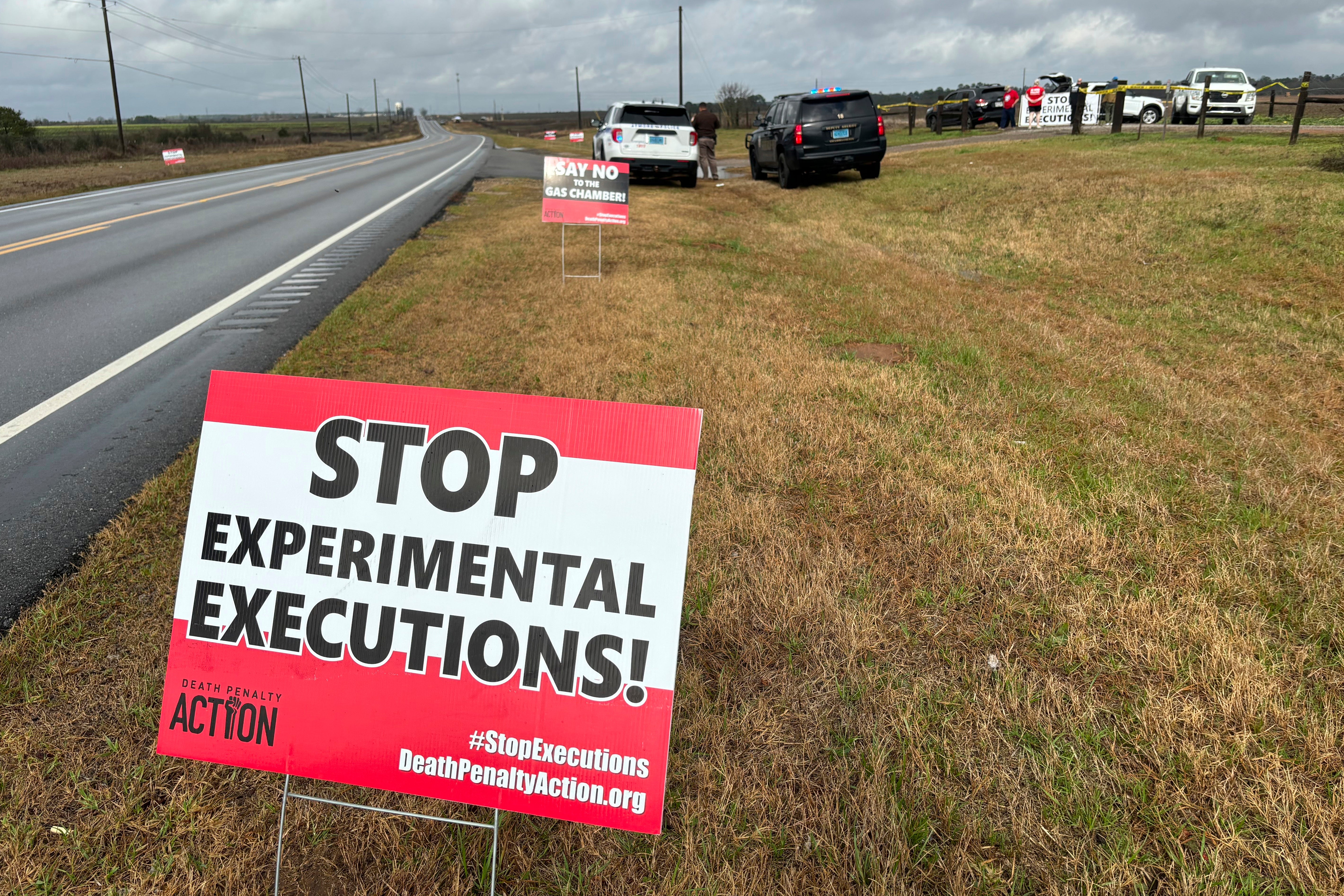 Anti-death penalty activists place signs along the road heading to Holman Correctional Facility