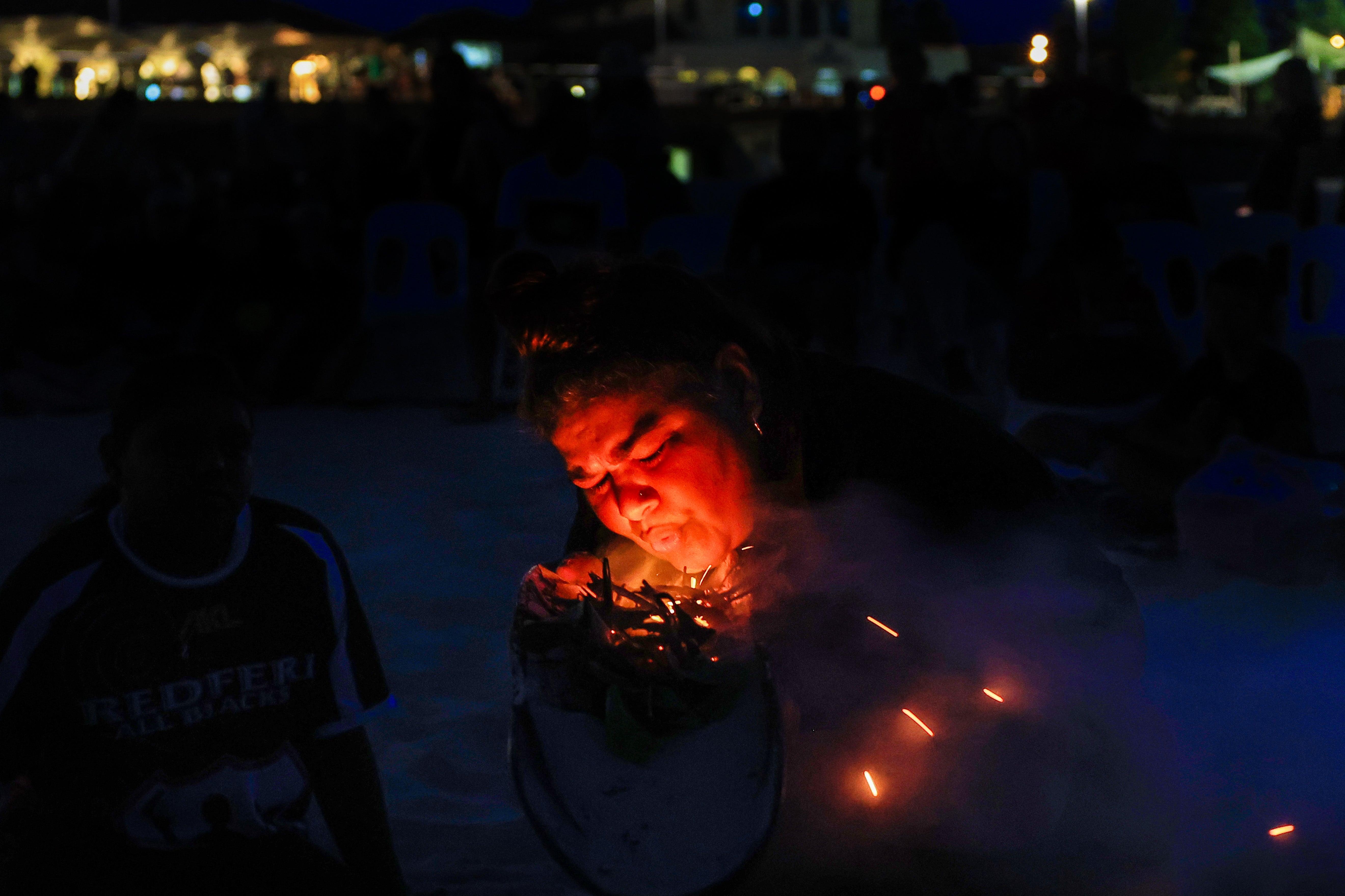 Rowena Welsh-Jarrett blows on native plants to produce smoke at Bondi Beach for a Dawn Reflection and Smoking Ceremony on 26 January, 2024