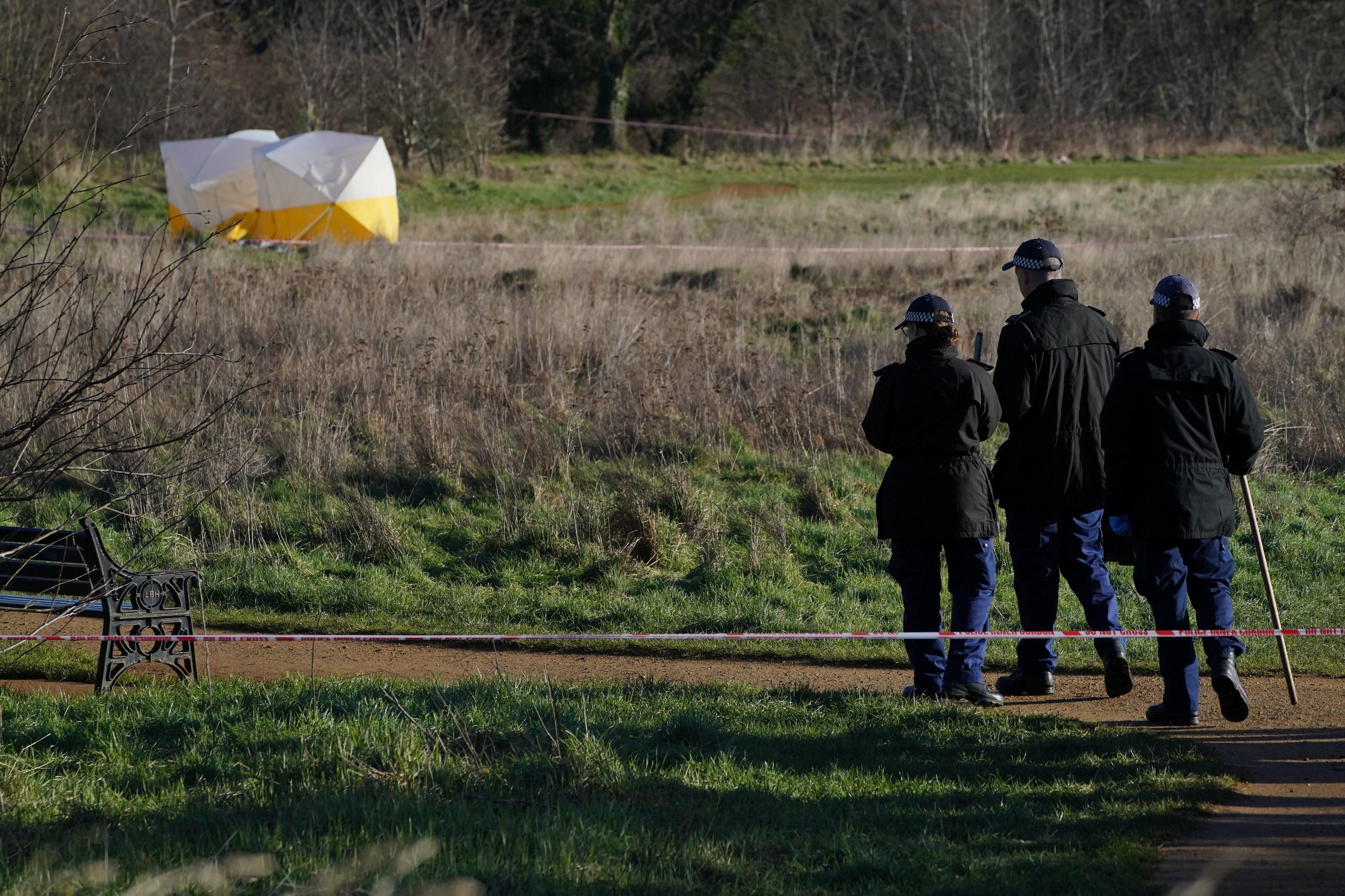 Forensic tents and a police search team at the scene at Hanworth Park, Feltham