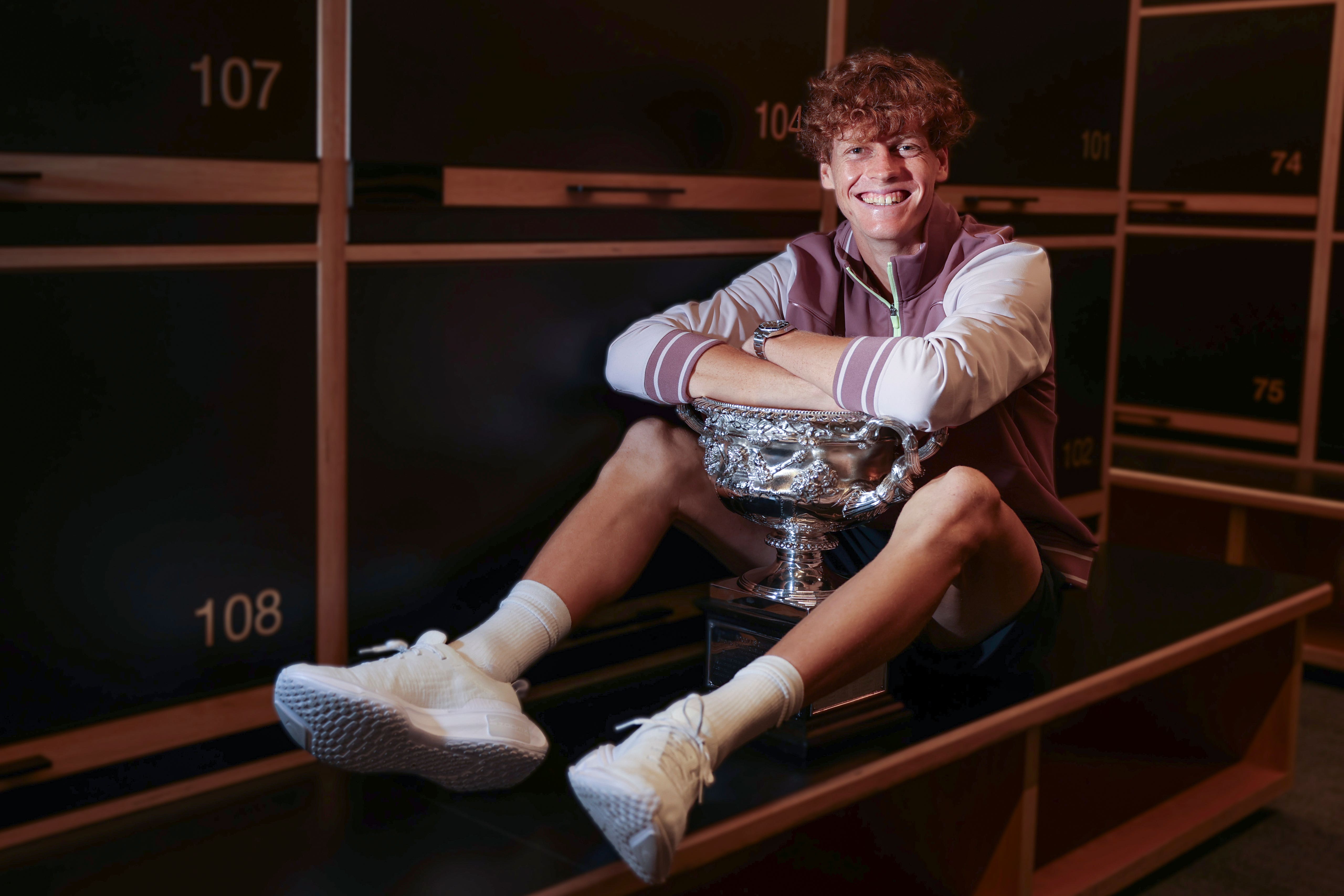 Jannik Sinner poses with the trophy in the locker room