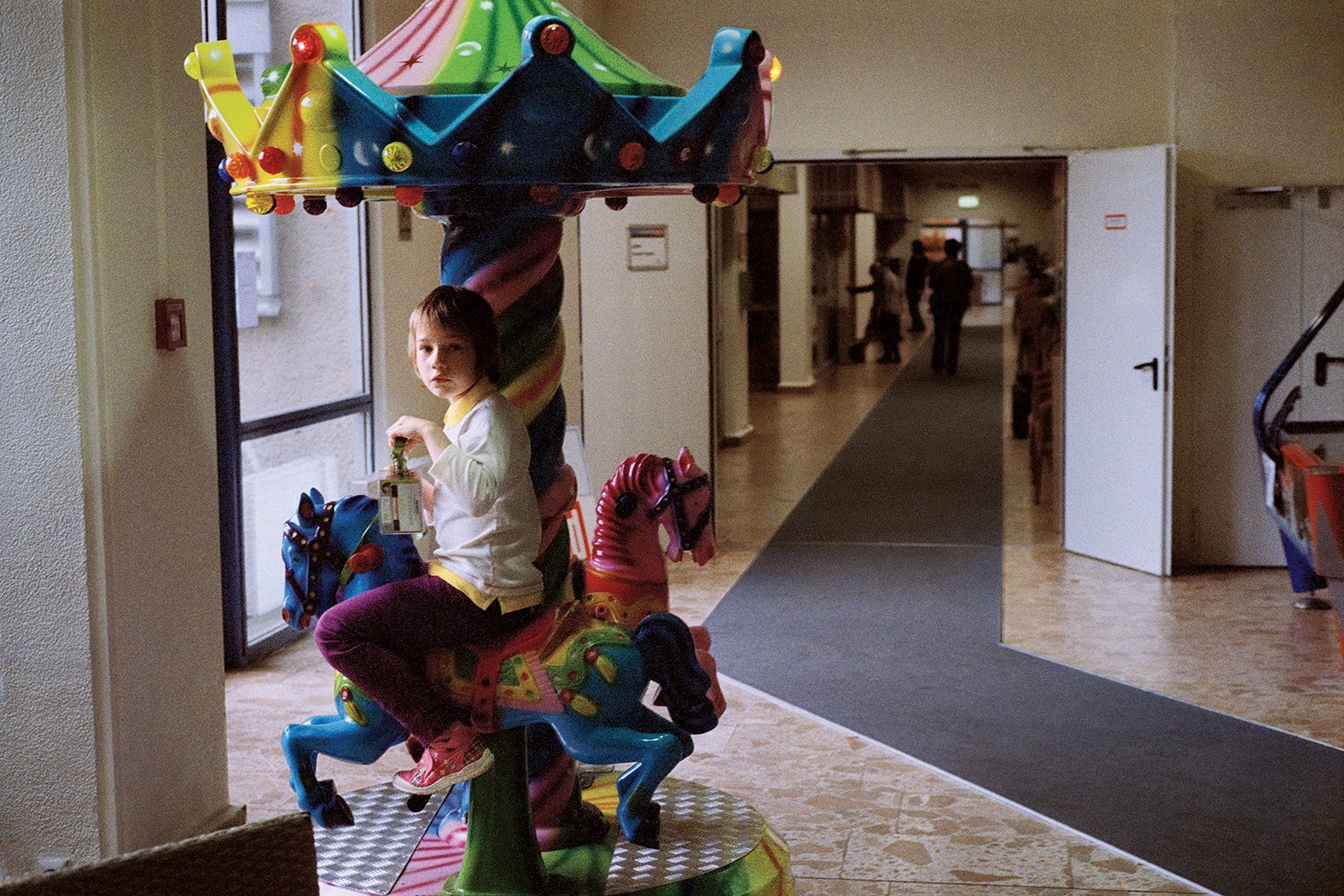 A boy rides a carousel in the corridor of a tourist hotel in Templin