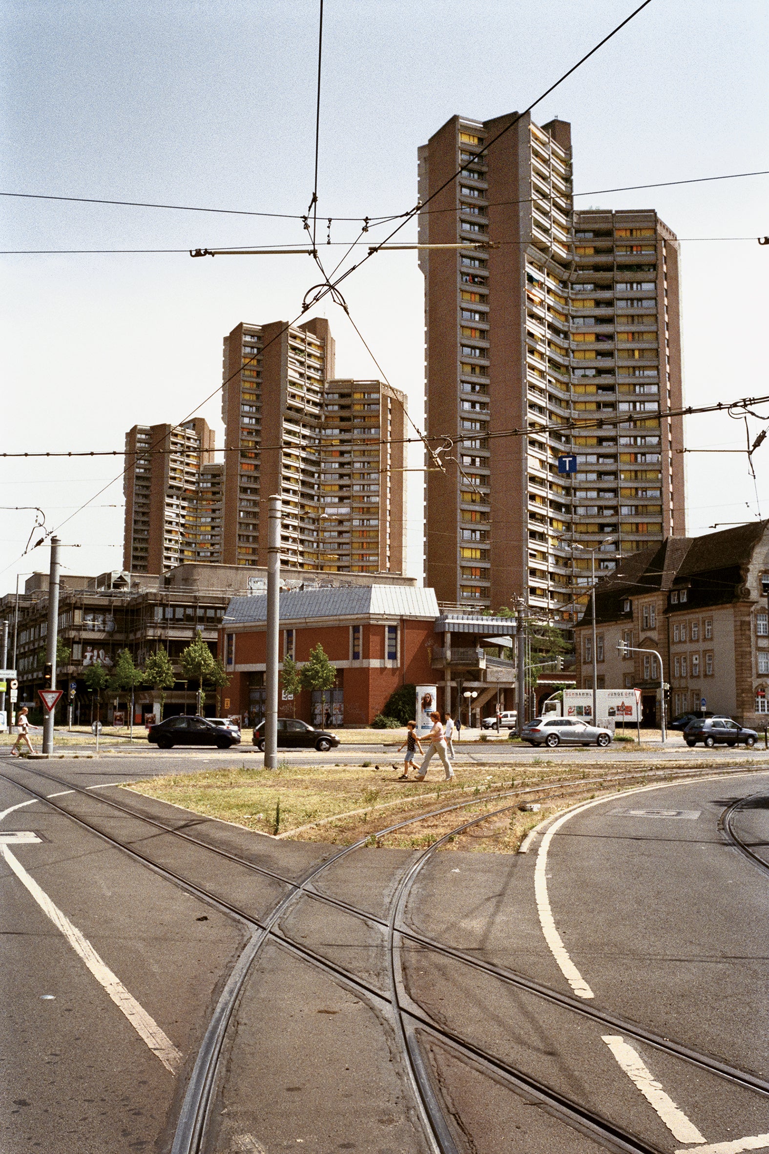 People cross the street in front of a brutalist building complex in the centre of Mannheim