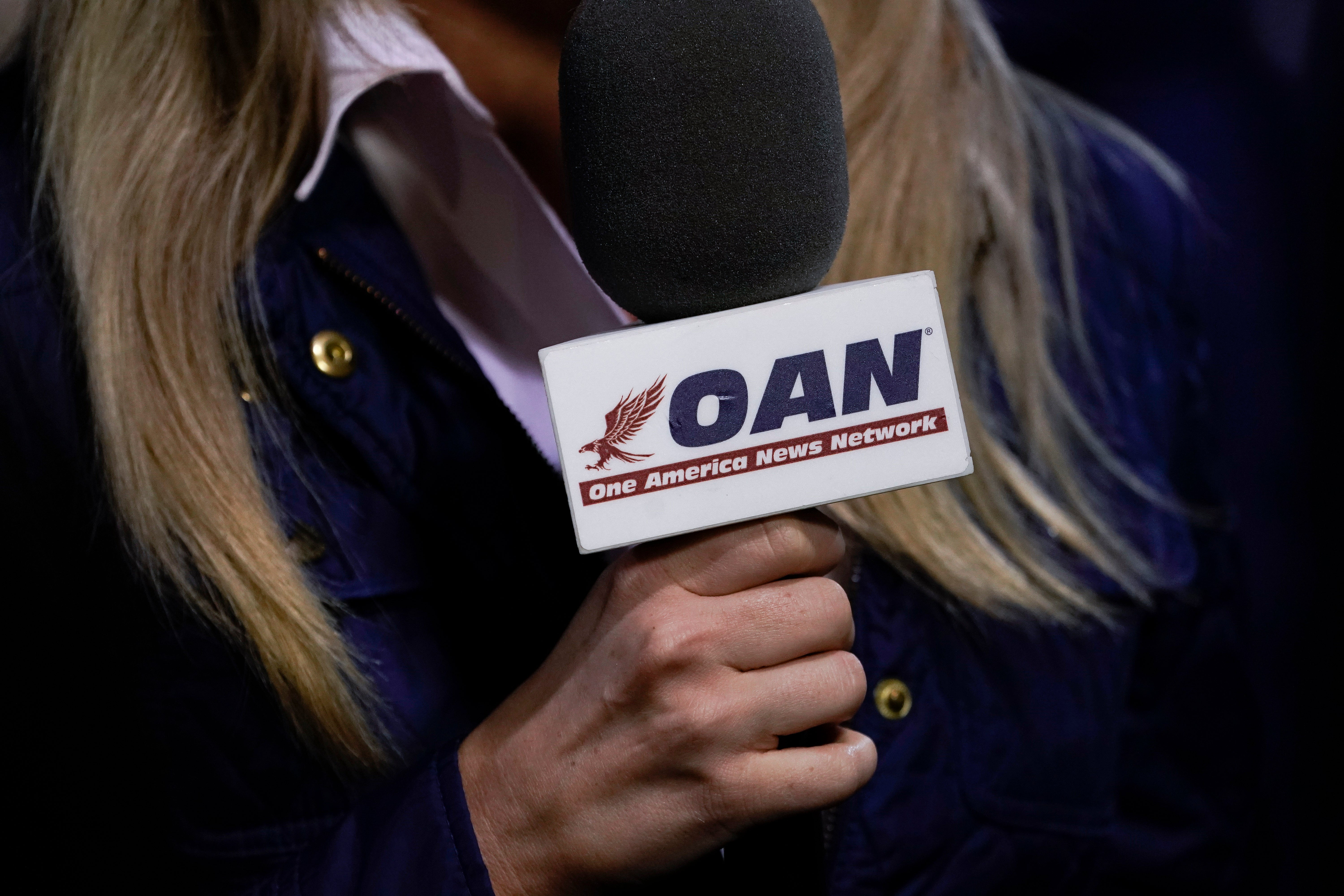 A reporter with One America News Network works at a Donald Trump campaign rally in Virginia in 2020.