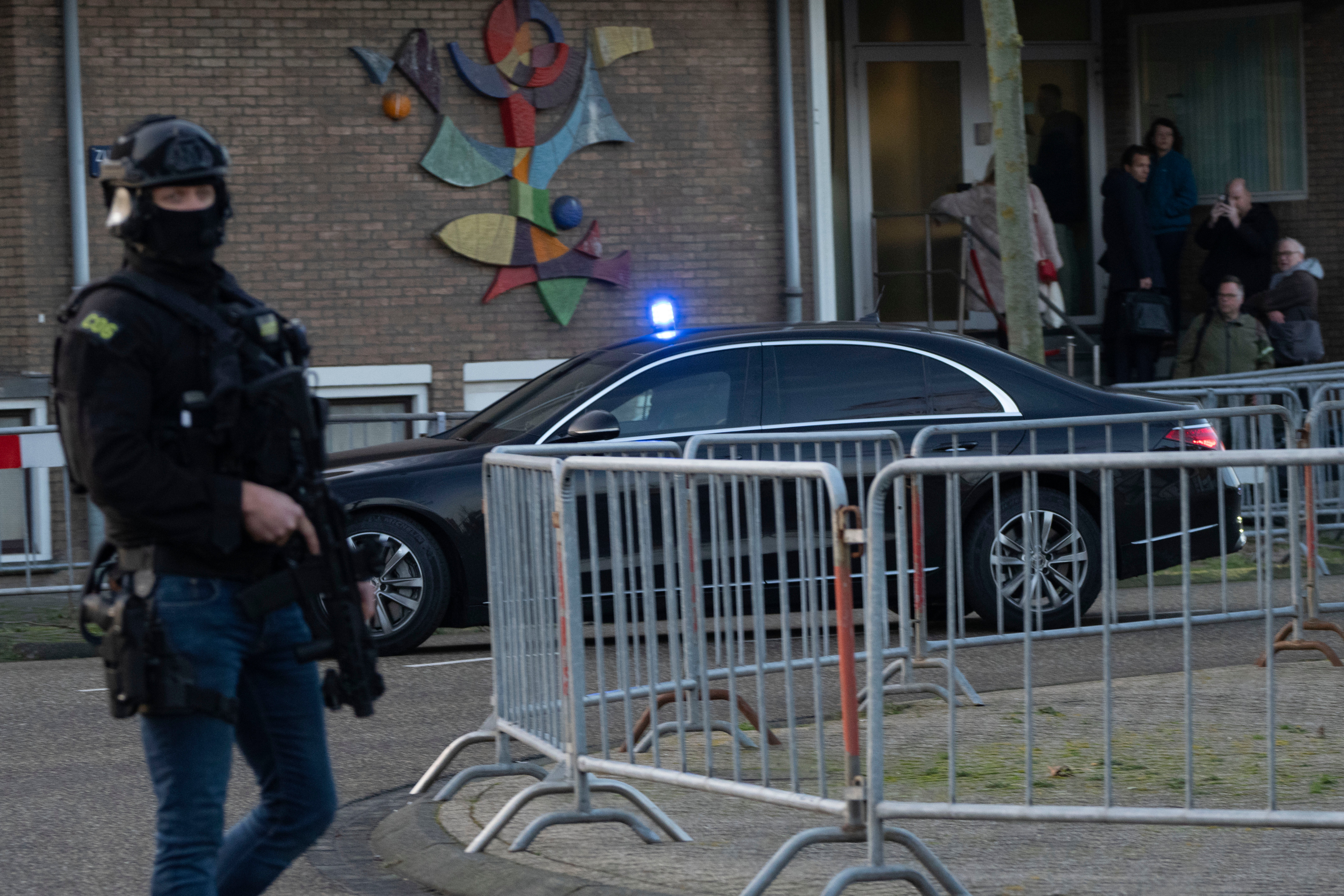 Masked and armed Dutch police guard a transport of some of the suspects who arrived a the high security court building where the trial opened in Amsterdam, Netherlands, Tuesday, Jan. 23, 2024
