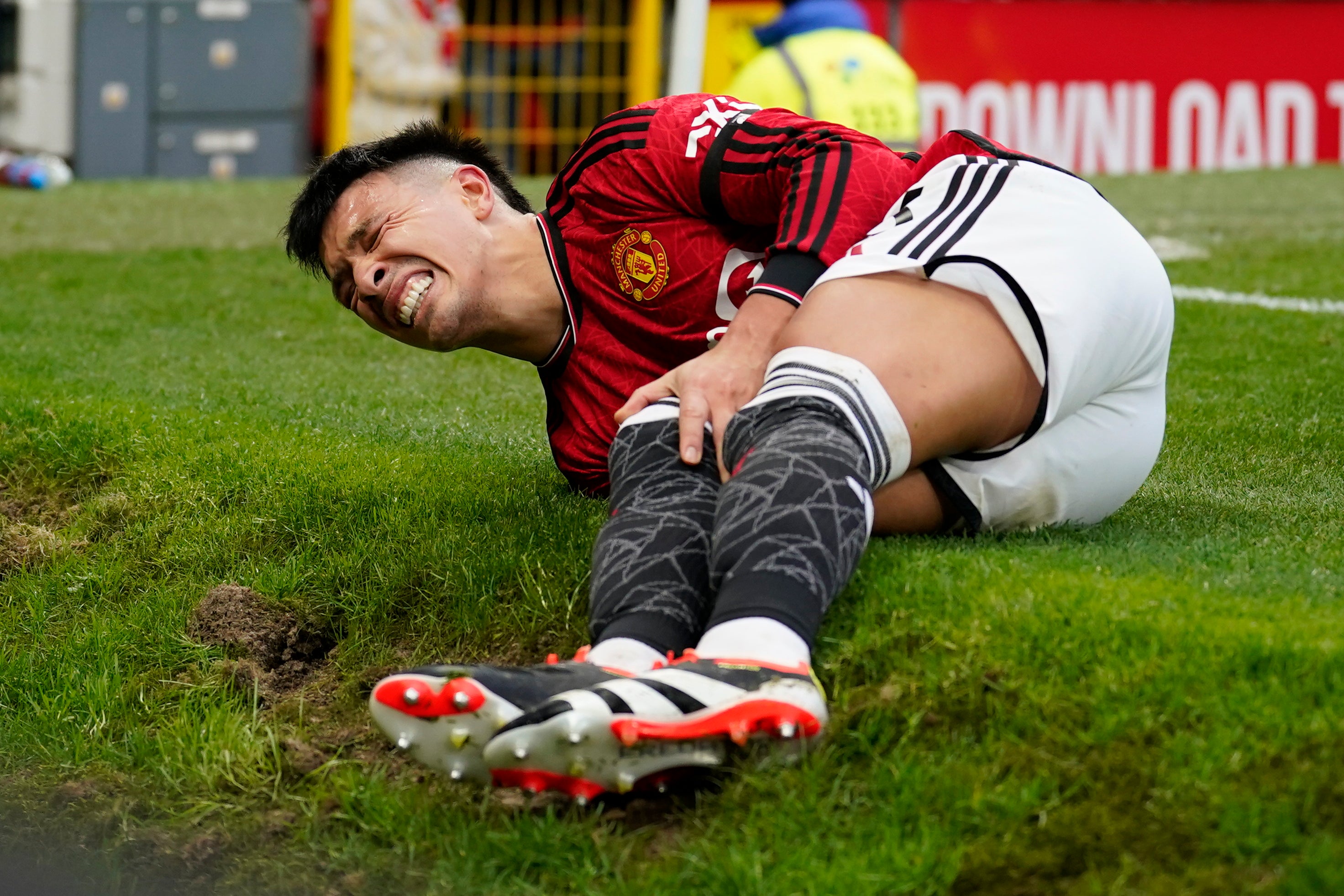 Lisandro Martinez holds his knee in pain after the incident