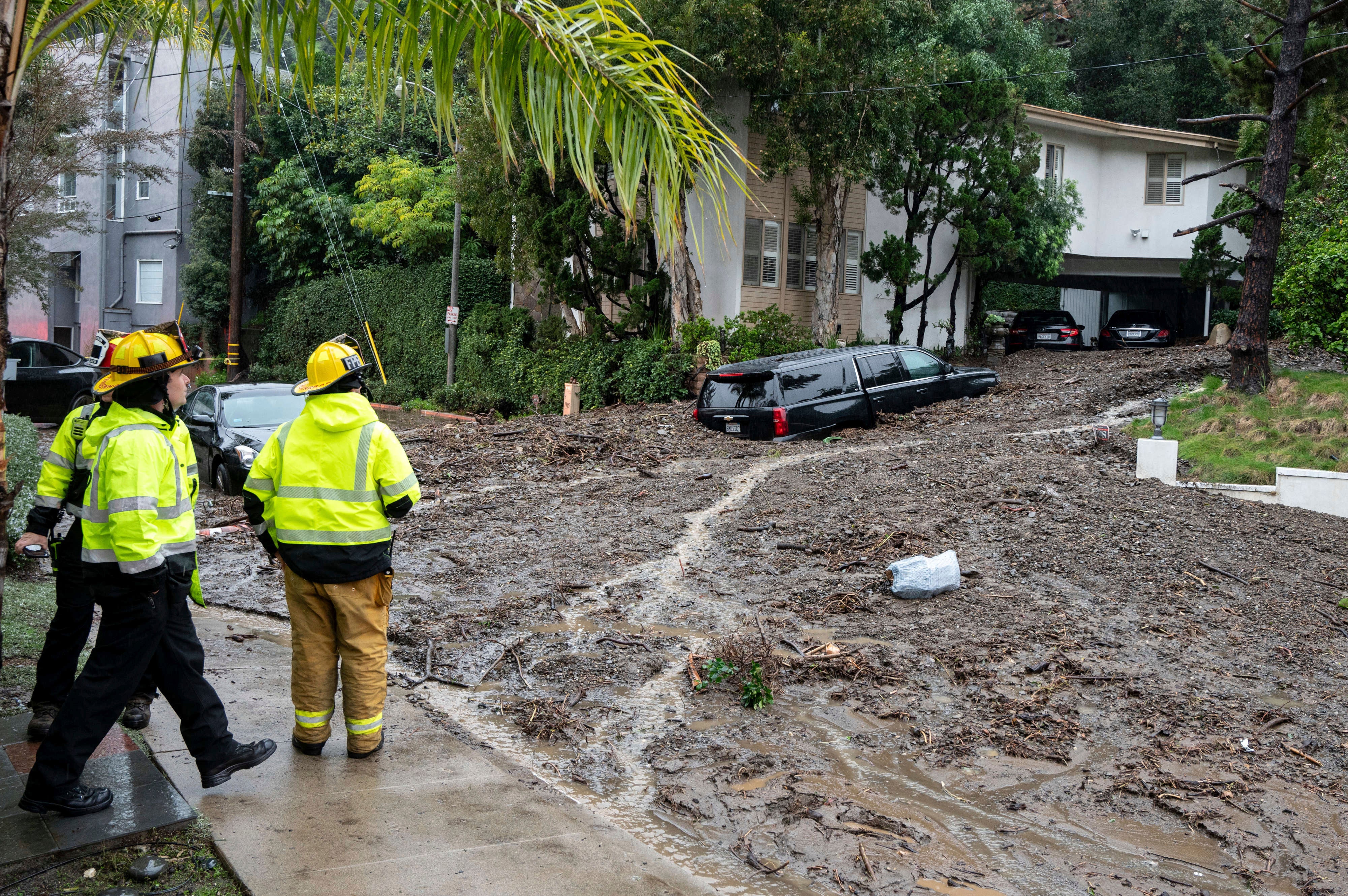 Firefighters look over damage from a large mudslide which occurred at the intersection of Beverly Drive and Beverly Place in the Beverly Crest area of Los Angeles on February 5