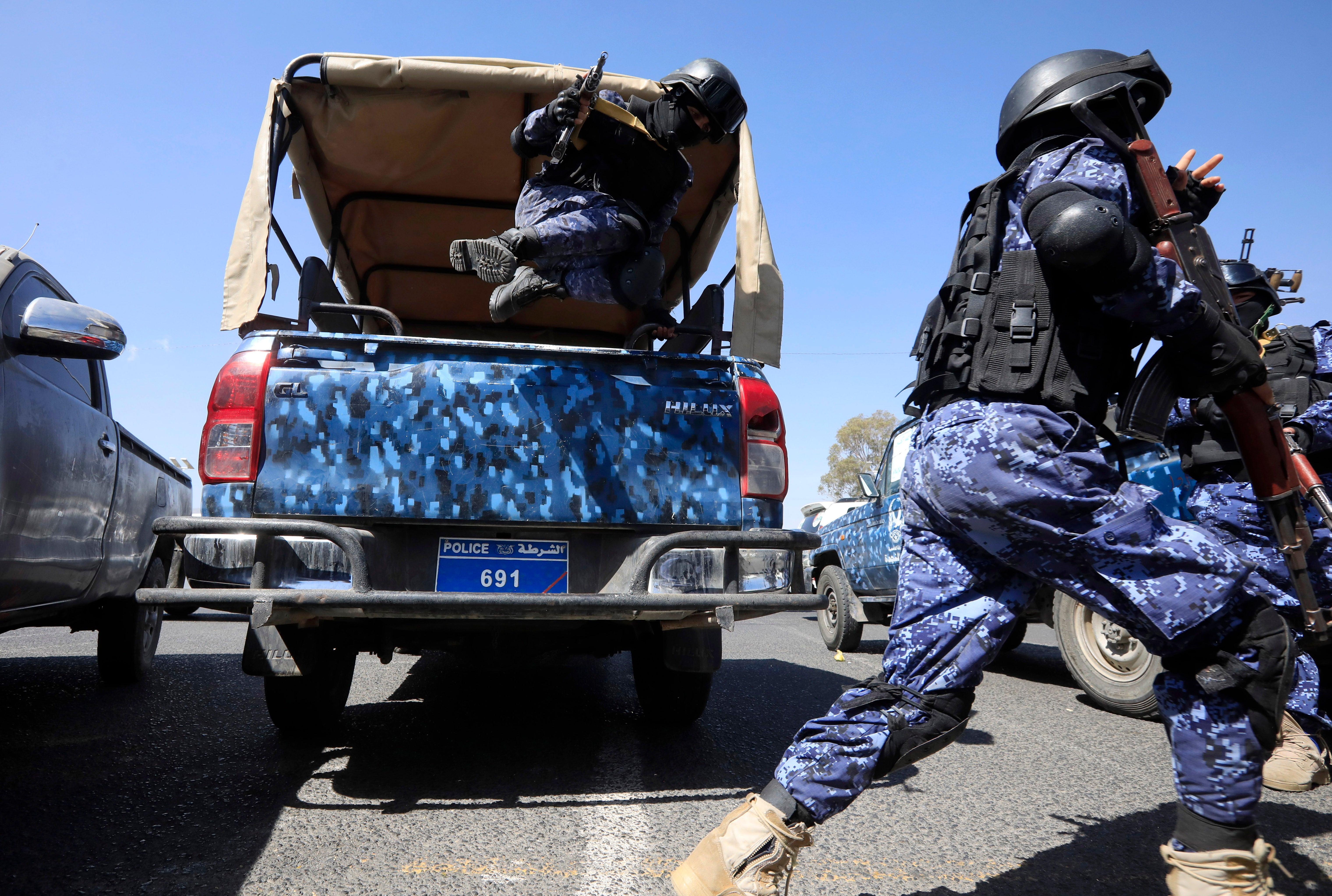 Armed Houthi soldiers jump off a pick-up vehicle while on patrol in a street in Sana’a, Yemen