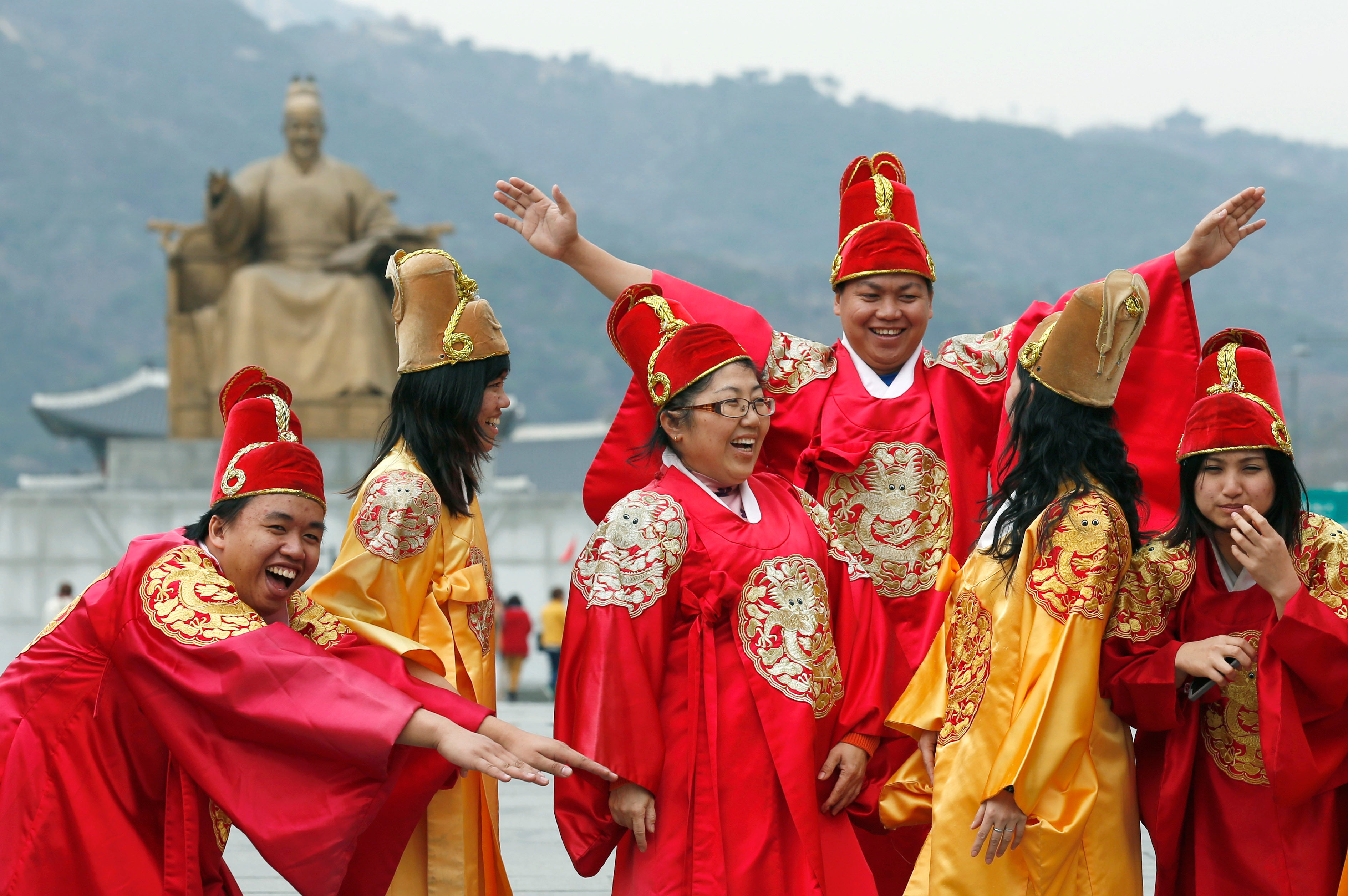 <p>File. Tourists wear royal robes while posing for pictures in front of a statue of King Sejong in Seoul, South Korea</p>