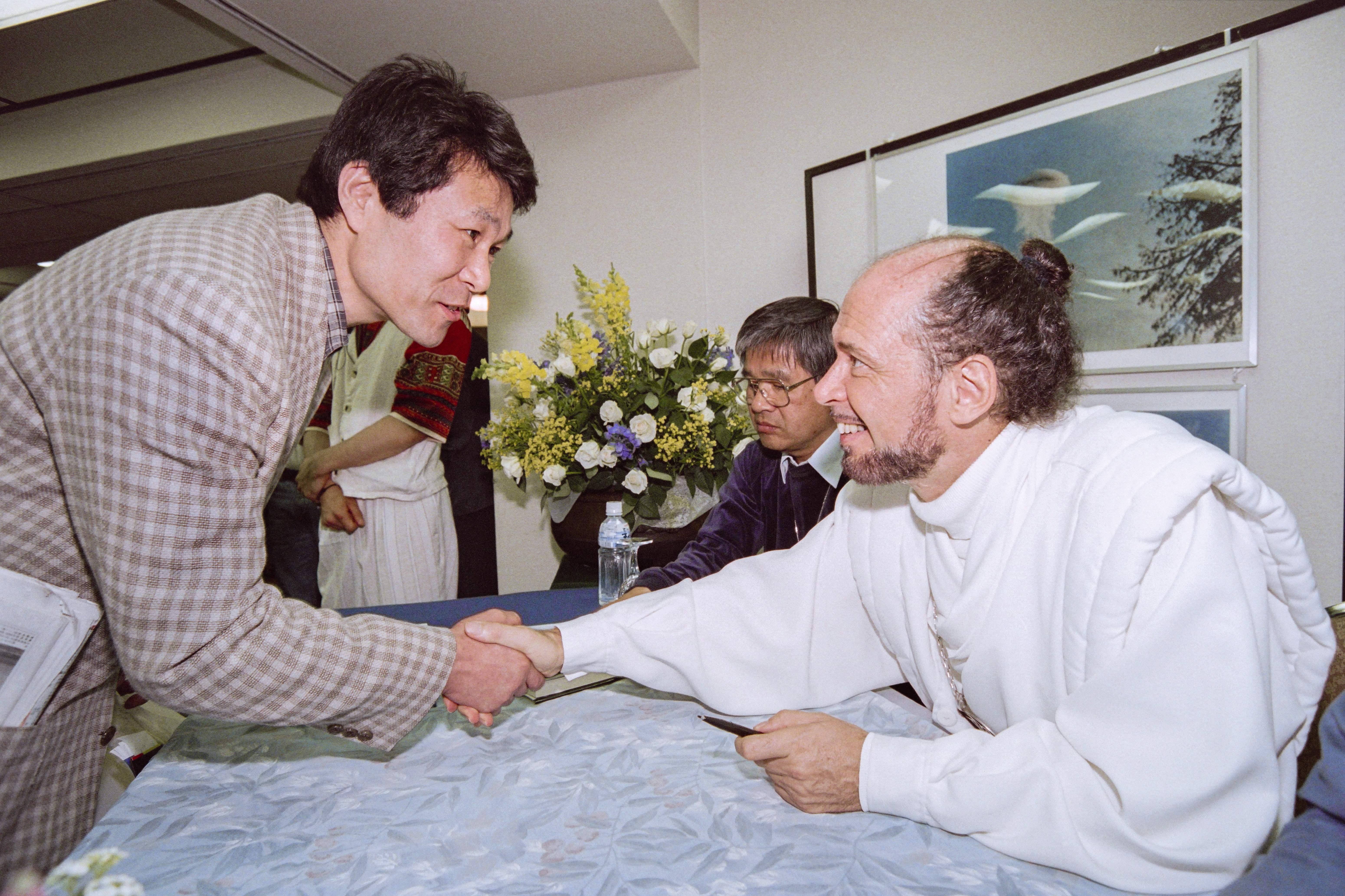 Claude Vorilhon shakes hands with someone during a seminar in Tokyo on 20 April 1997