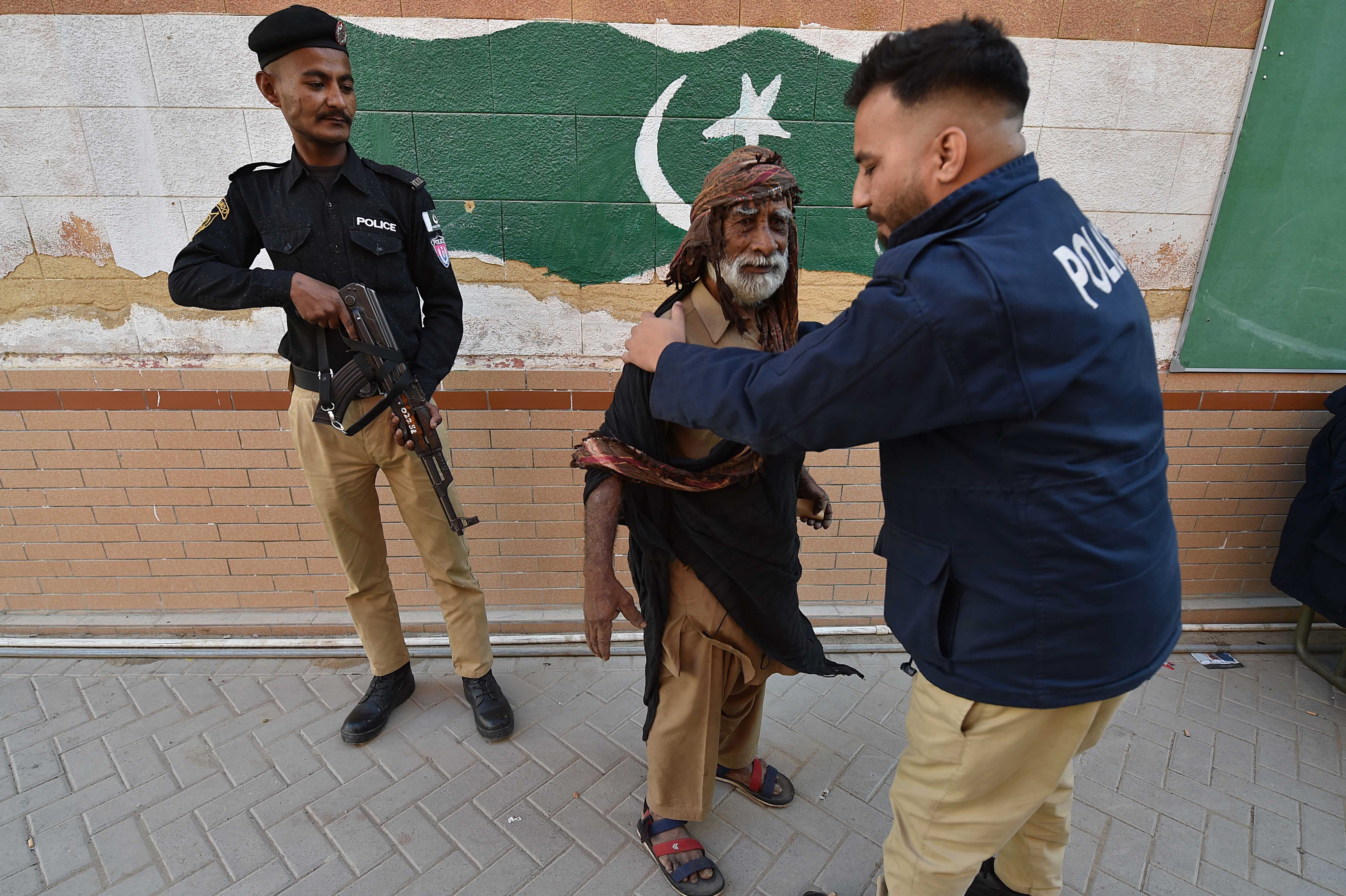 Pakistani security officials stand guard at a polling station, during general elections in Karachi